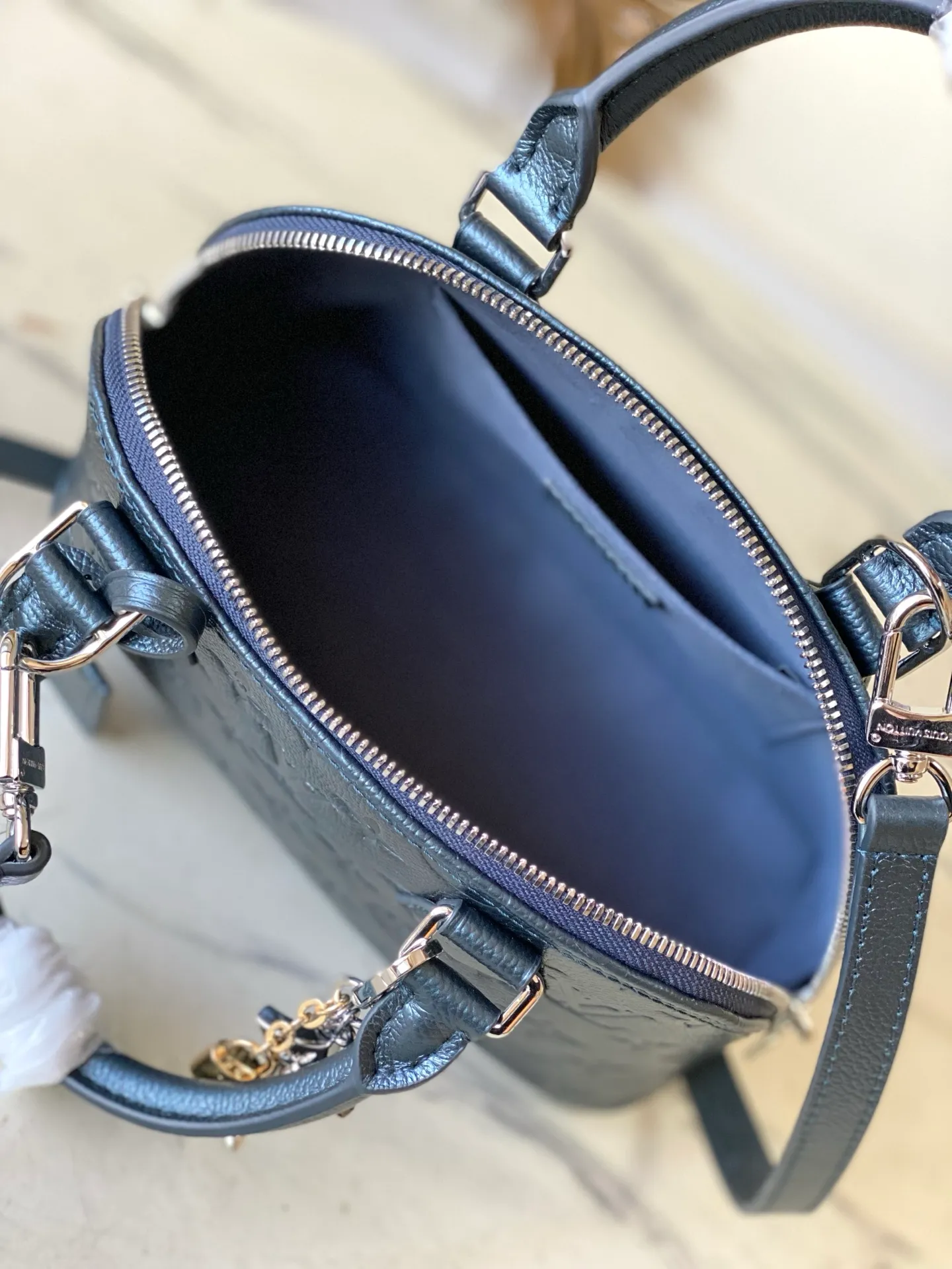 💰1140 (top layer leather) Top original order M26686 Pearlescent Blue This LV Ski version of the Alma BB bag is inspired by the magic of winter nights and decorated with this season’s exclusive sparkling hue. The model is made of Monogram Empreinte leather and features an iridescent finish and a removable tri-color metal charm that can be attached to other accessories. Among the signature details is a key bell, as well as a keyed silver padlock that pays homage to the house's suitcase heritage. Dimensions: 23.5 x 17.5 x 11.5 cm