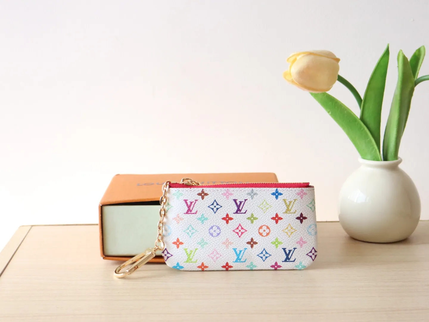 13664 Tricolor Coin Purse🌟P84 This replica Louis Vuitton x Murakami series key coin purse is colorful and made of coated canvas. The vibrant iconic Monogram pattern reinterprets the brand logo with the theme of Japanese artist Takashi Murakami in rainbow tones. The key coin purse has a silver zipper and is equipped with a chain strap and hook buckle to store keys securely. 12 x 7 x 1.5 cm (length x height x width)