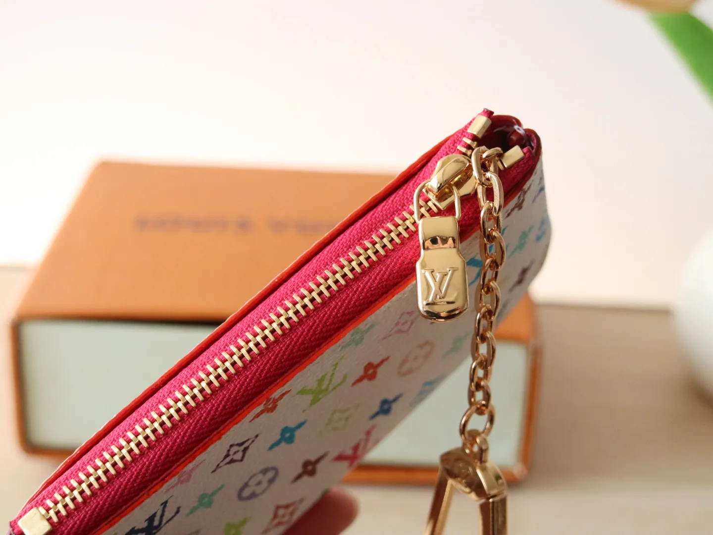 13664 Tricolor Coin Purse🌟P84 This replica Louis Vuitton x Murakami series key coin purse is colorful and made of coated canvas. The vibrant iconic Monogram pattern reinterprets the brand logo with the theme of Japanese artist Takashi Murakami in rainbow tones. The key coin purse has a silver zipper and is equipped with a chain strap and hook buckle to store keys securely. 12 x 7 x 1.5 cm (length x height x width)
