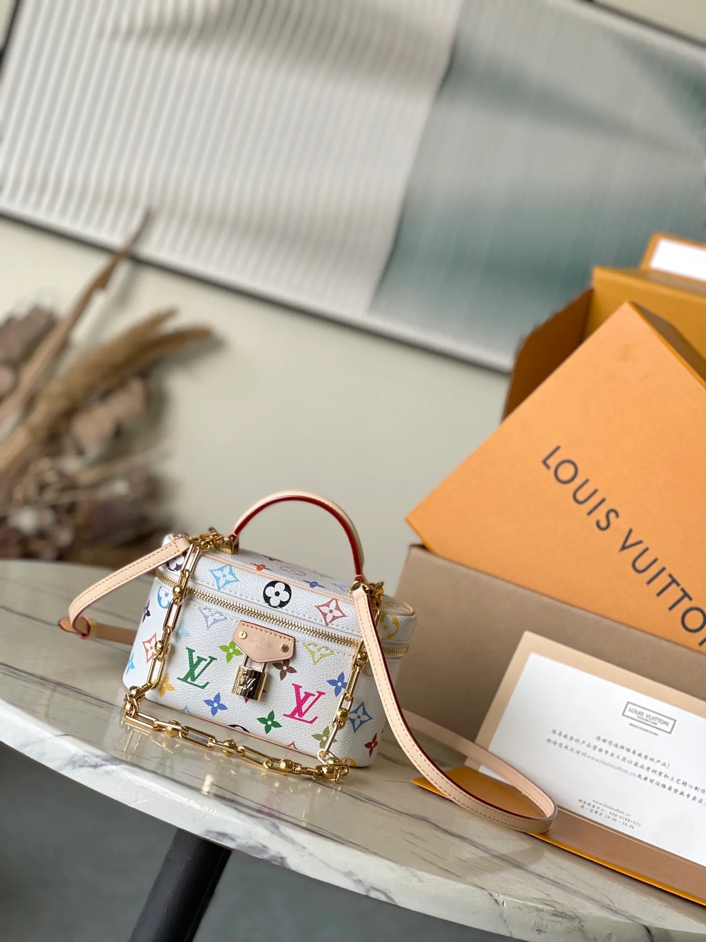 💰960 Top original order M13662 This Vanity Pouch handbag is from the Louis Vuitton x Murakami reissue series, reinterpreting the brand's classic Monogram pattern with the artist's bright colors. The coated canvas is trimmed with cow leather, and the zipper closure, detachable chain and LV-engraved padlock add a metallic sheen. Dimensions: 19 × 11.5 × 6.5 cm