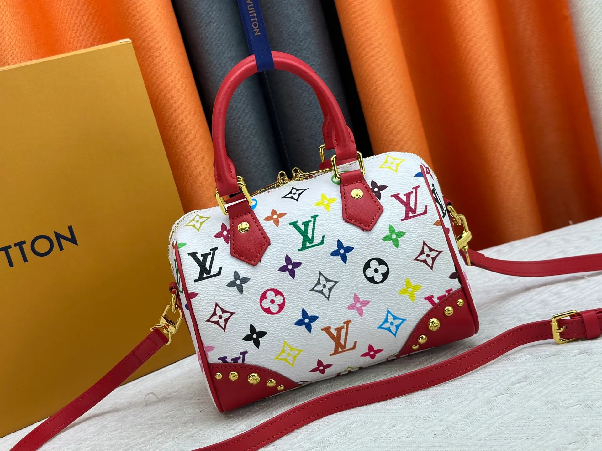 P260 upgraded original M58953 M46234 M46222 Speedy Bandoulière 20 handbag is made of soft coated canvas, and the full-length Monogram pattern is traced in colorful rainbow tones, highlighting the smart style of the Louis Vuitton x Murakami reissue series. The Toron handle and detachable shoulder strap are constructed of cow leather, the metal corners recall classic luggage elements, and the bow-shaped key bag and padlock add brand touches. Dimensions: 20.5 x 13.5 x 12.0 cm (length x height x width)