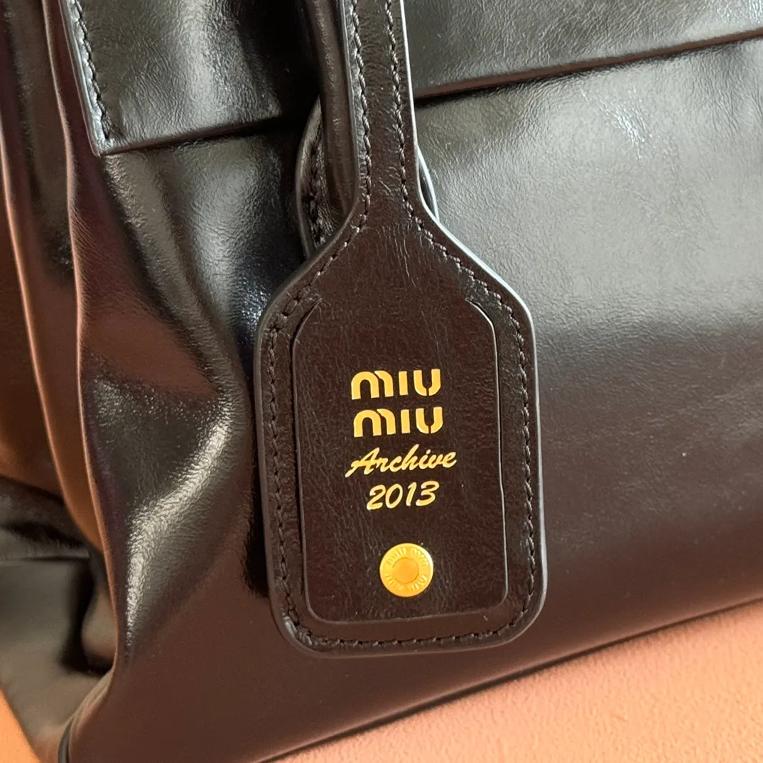 p1660💋💋💋【Configure full counter package】Solitaire Small Handbag in Glossy Leather: 5BA301 Structured lines and exquisite details define this handbag, inspired by MiuMiu’s 2006 archives. An elegant style that combines classic and experimental is enhanced by the iconic logo on the front and a shiny finish. ·With handles ·Front and back pockets ·Golden hardware ·With zipper pocket and patch pockets ●Front lettering logo Width: 25cm, Height: 18cm, Length: 10cm?