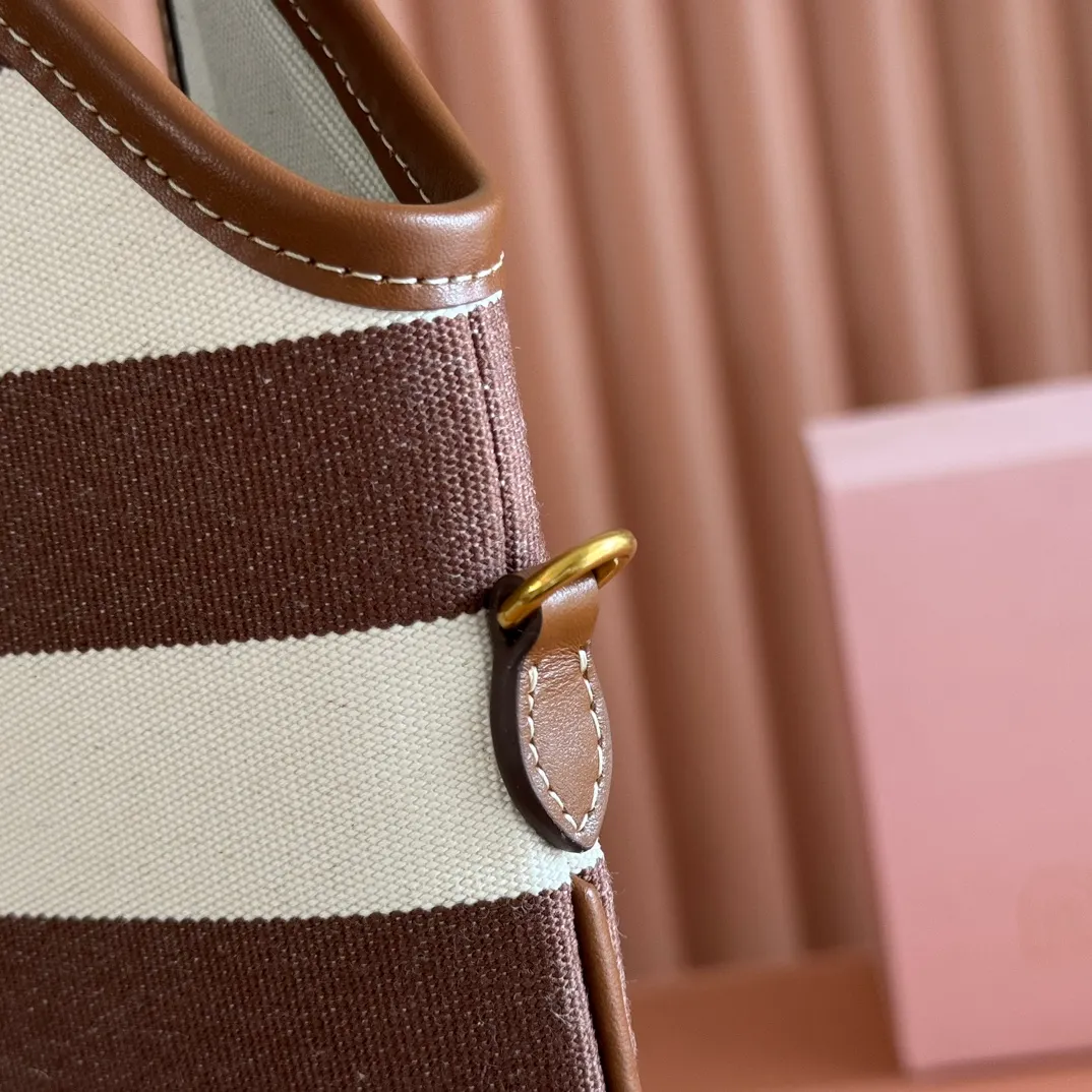 p1300. 💋💋💋【Full set of packages at the counter】𝗠𝗜𝗨𝗠𝗜𝗨 𝗙𝗪𝟮𝟱 𝗡𝗲𝘄 𝗮𝗿𝗿𝗶𝘃𝗮𝗹!      When striped canvas meets hobo's lazy gene, it grabs the first wave in autumn and winter. The relaxed feeling of commuting is directly capped. Classic blue and white nautical striped canvas × Italian calfskin piping. Flexible bag body hangs naturally. Tote capacity + Hobo's lazy feeling two-in-one. It looked like it was 𝗷𝗮𝗰𝗸𝗲𝘁 canvas, but when I touched the edge of the leather, I realized it was 𝗹𝘂𝘅𝘂𝗿𝘆!   The Ju Neng suit still hasn’t collapsed! 𝗵𝗼𝗯𝗼Bag shape looks slim 𝟭𝟬𝟬% 5BG231 stripes Size: 35×40cm