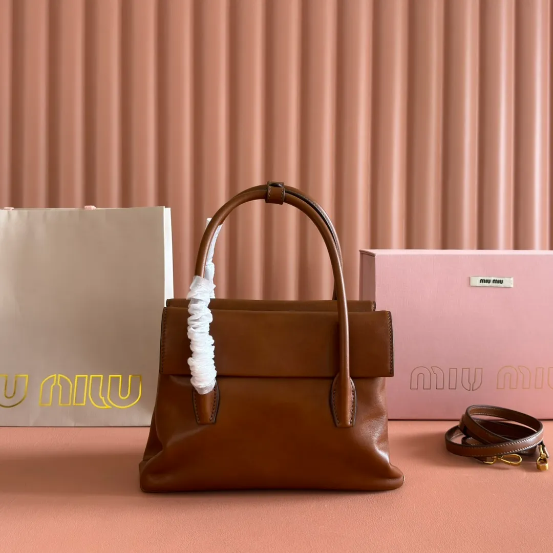p1660💋💋💋【Configuring full counter package】Vintage cow leather Solitaire small handbag: 5BA301 Structured lines and exquisite details define this handbag, inspired by MiuMiu’s 2006 archives. An elegant style that combines classic and experimental is enhanced by the iconic logo on the front and a shiny finish. ·With handles ·Front and back pockets ·Golden hardware ·With zipper pocket and patch pockets ●Front lettering logo Width: 25cm, Height: 18cm, Length: 10cm?