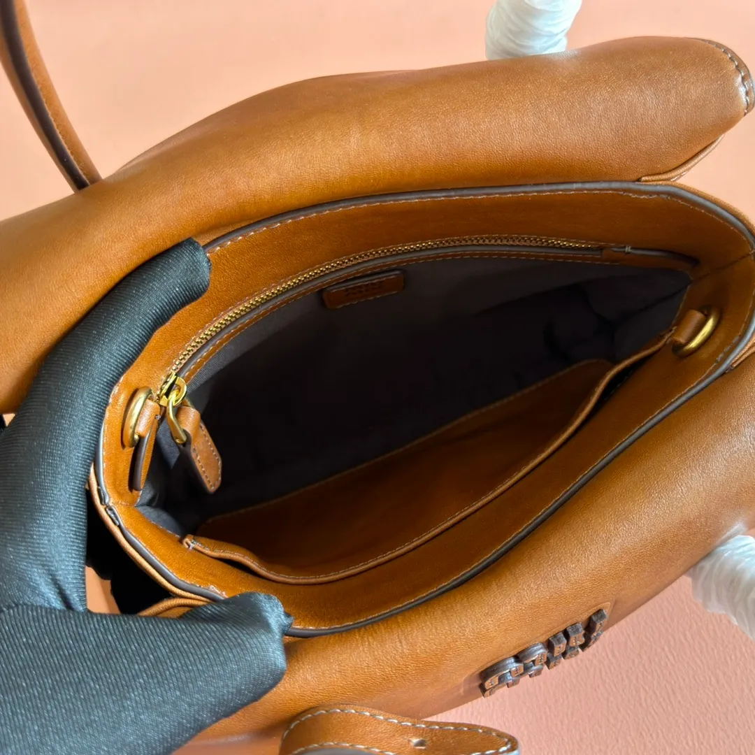 p1660💋💋💋【Configuring full counter package】Vintage cow leather Solitaire small handbag: 5BA301 Structured lines and exquisite details define this handbag, inspired by MiuMiu’s 2006 archives. An elegant style that combines classic and experimental is enhanced by the iconic logo on the front and a shiny finish. ·With handles ·Front and back pockets ·Golden hardware ·With zipper pocket and patch pockets ●Front lettering logo Width: 25cm, Height: 18cm, Length: 10cm?