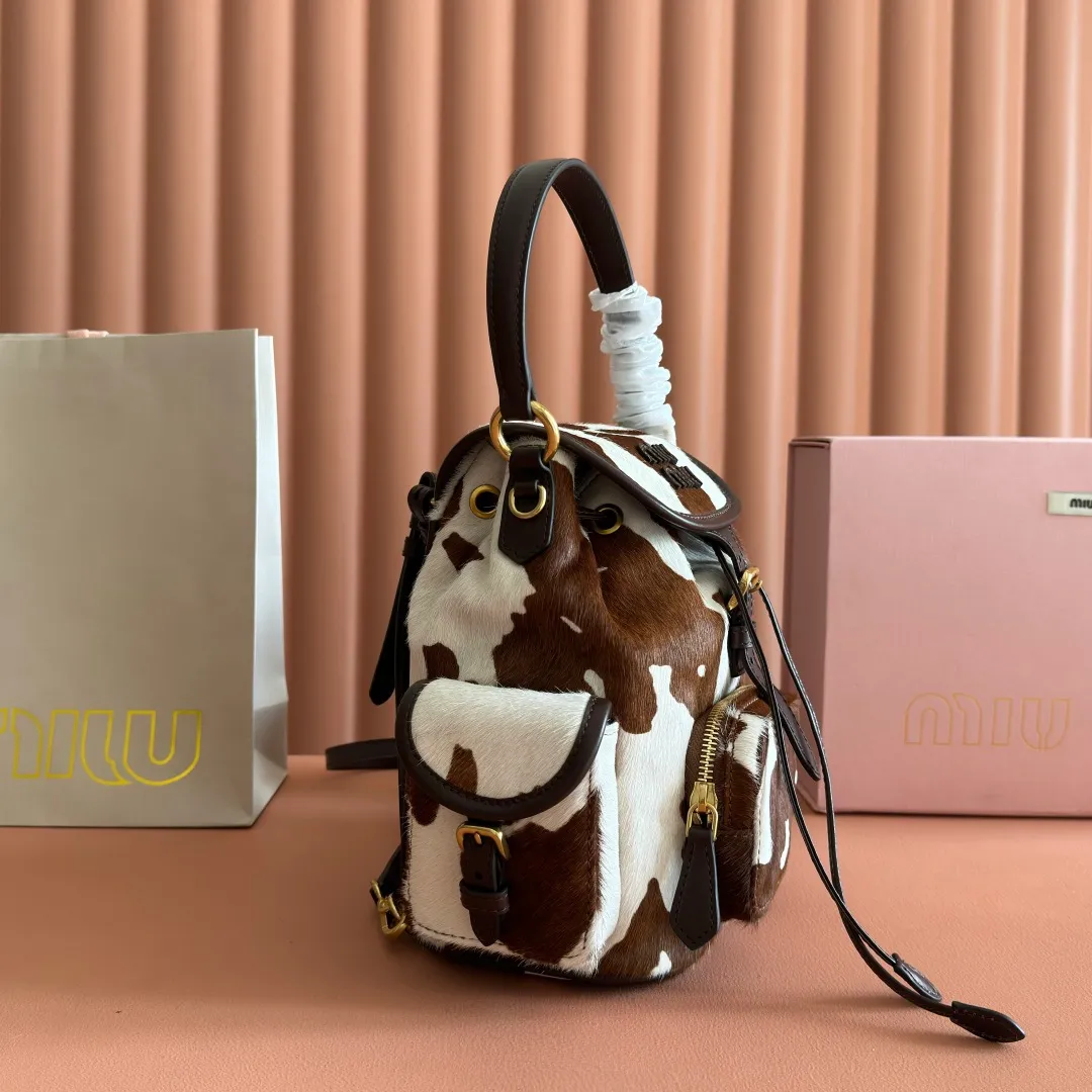 p1900💋💋💋【Original leather configuration counter complete package】𝐌𝐈𝐔𝐌𝐈𝐔 New cow pattern backpack Miu Miu's cow pattern backpack perfectly combines retro wildness and girly sweetness. The brown and white contrasting cow pattern fur material comes with an eye-catching buff, and is matched with the iconic logo embossing, showing the brand style in every detail; the drawstring flap design combines practicality with retro charm, and the combination of leather handles and shoulder straps, 🉑hand-held🉑shoulder-carrying, easily adapts to different wearing scenarios. Whether paired with casual denim or a sweet girl-style skirt, it can instantly inject a personal touch into the look and is the finishing touch to unlock niche fashion. Style number: 5B043 Small size: bottom length 23x height 25x width 13cm