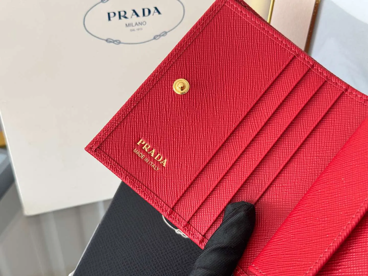 Prada women's two-fold short clip, with coin pocket and coin pocket. Model 1M0204, cross-grain cowhide. Size: 11.2x9.5cm. Simple and practical to enhance personal taste.