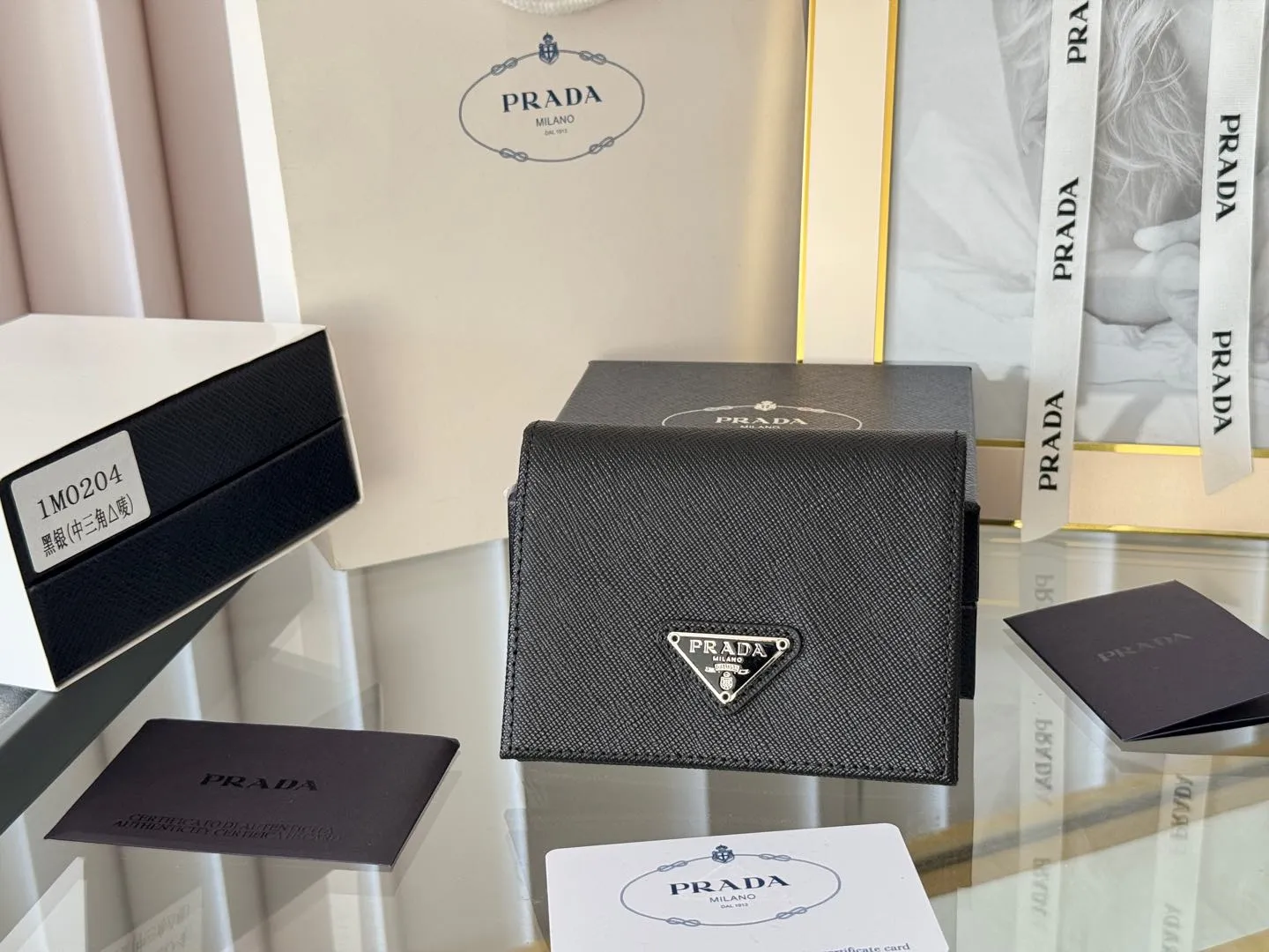 Prada women's two-fold short clip, with coin pocket and coin pocket. Model 1M0204, cross-grain cowhide. Size: 11.2x9.5cm. Simple and practical to enhance personal taste.