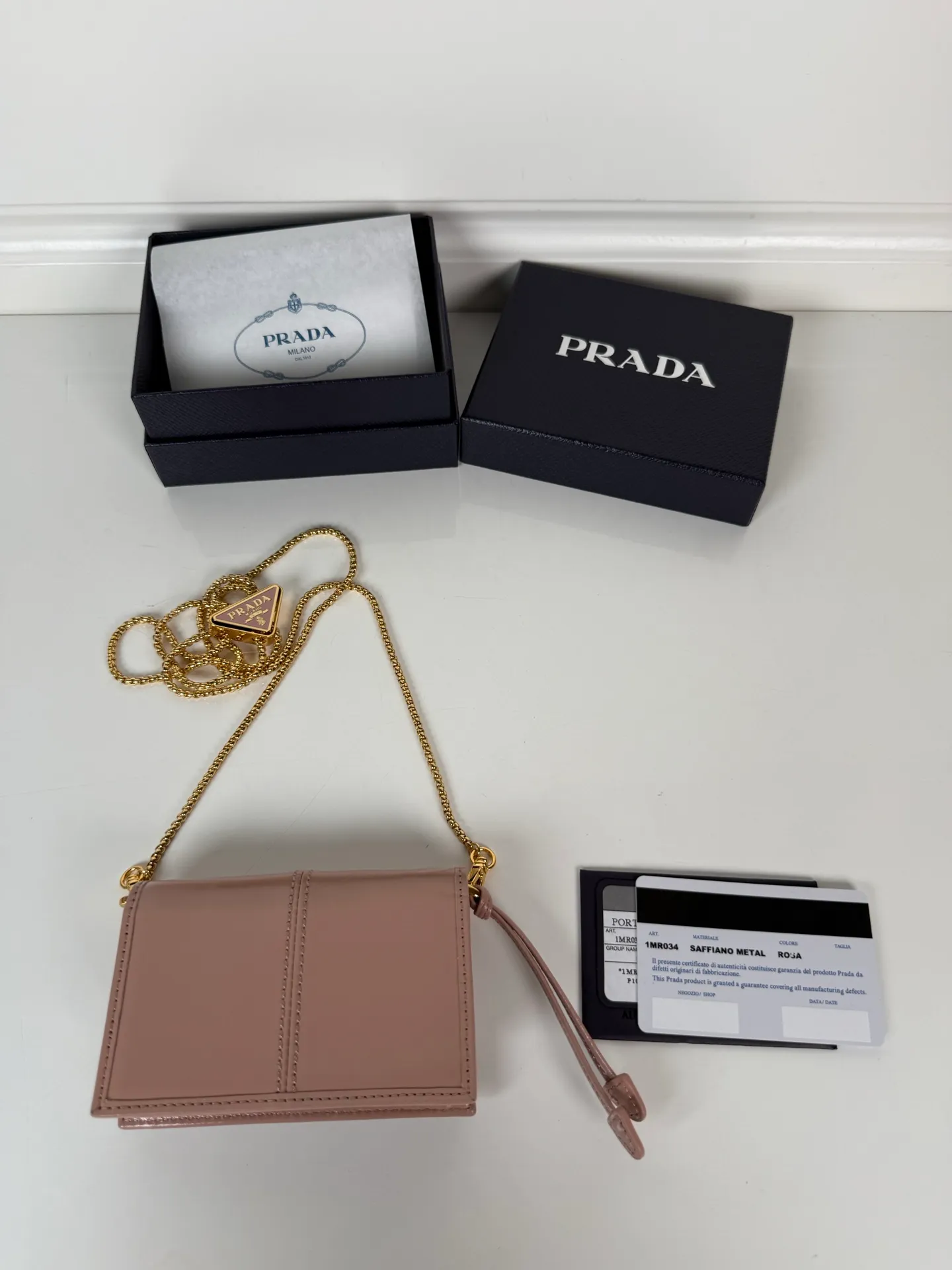 💰900; P Home ➡️Multifunctional mini backpack for women, model 1MR034, flip-top card holder with detachable Saffiano leather shoulder strap, metal triangular micro-mark decorating the front, size 11.5 x8 x2.5cm, two card slots inside, snap closure, in summer it is a mini backpack, in winter it can be turned into a small card holder by removing the shoulder strap, super practical and worth owning👍