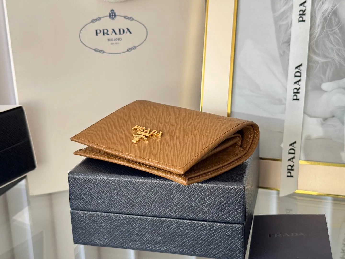 Prada women's two-fold short clip, with coin pocket and coin pocket. Model 1M0204, cross-grain cowhide. Size: 11.2x9.5cm. Simple and practical to enhance personal taste.