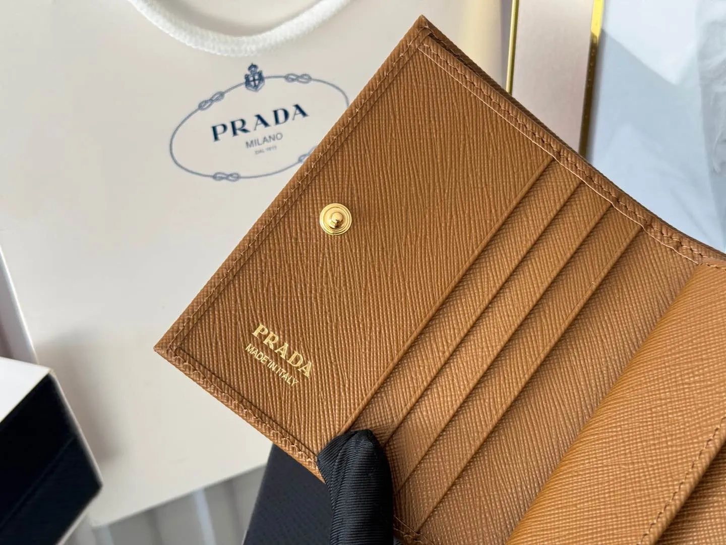 Prada women's two-fold short clip, with coin pocket and coin pocket. Model 1M0204, cross-grain cowhide. Size: 11.2x9.5cm. Simple and practical to enhance personal taste.
