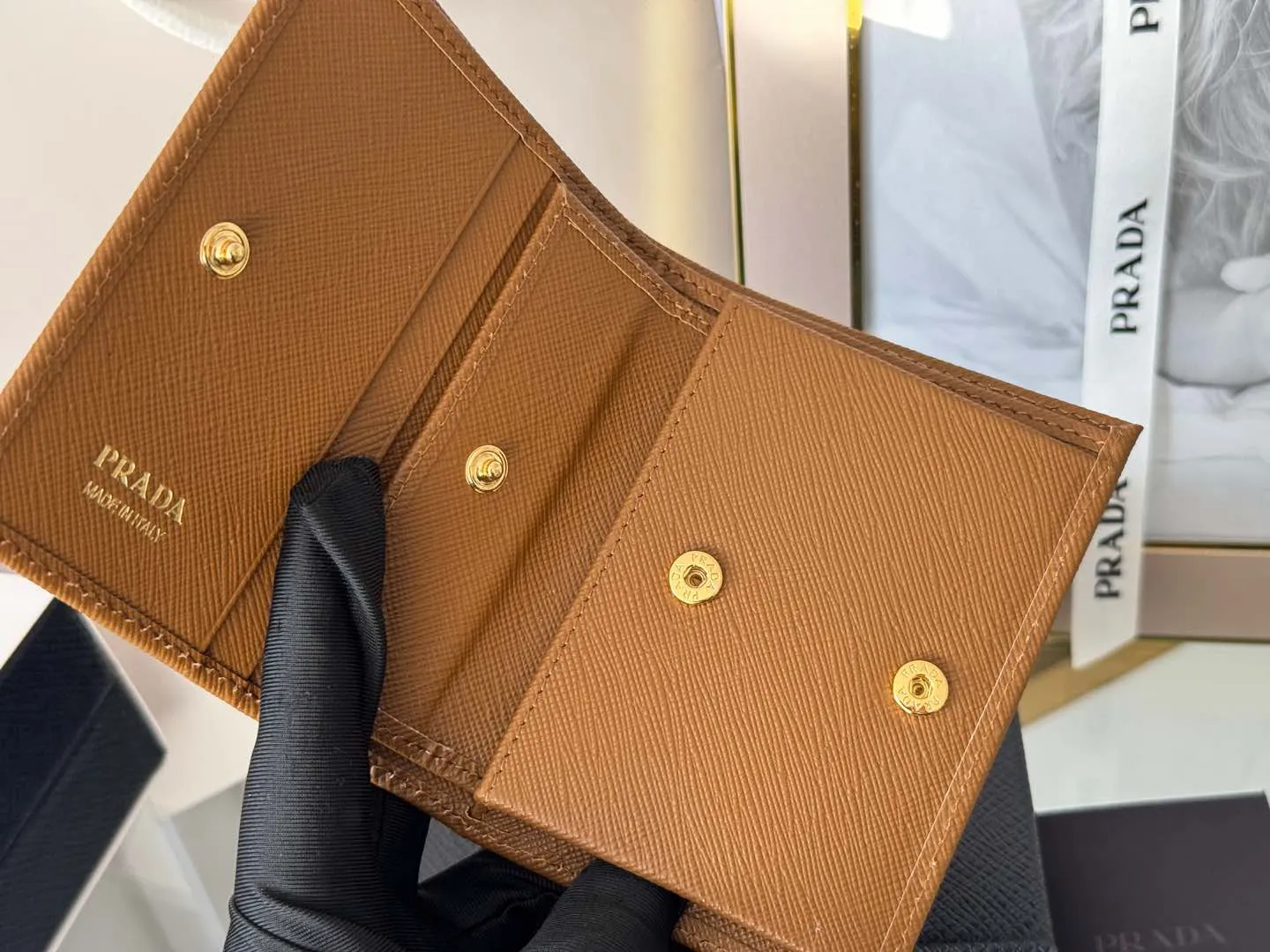 Prada women's two-fold short clip, with coin pocket and coin pocket. Model 1M0204, cross-grain cowhide. Size: 11.2x9.5cm. Simple and practical to enhance personal taste.