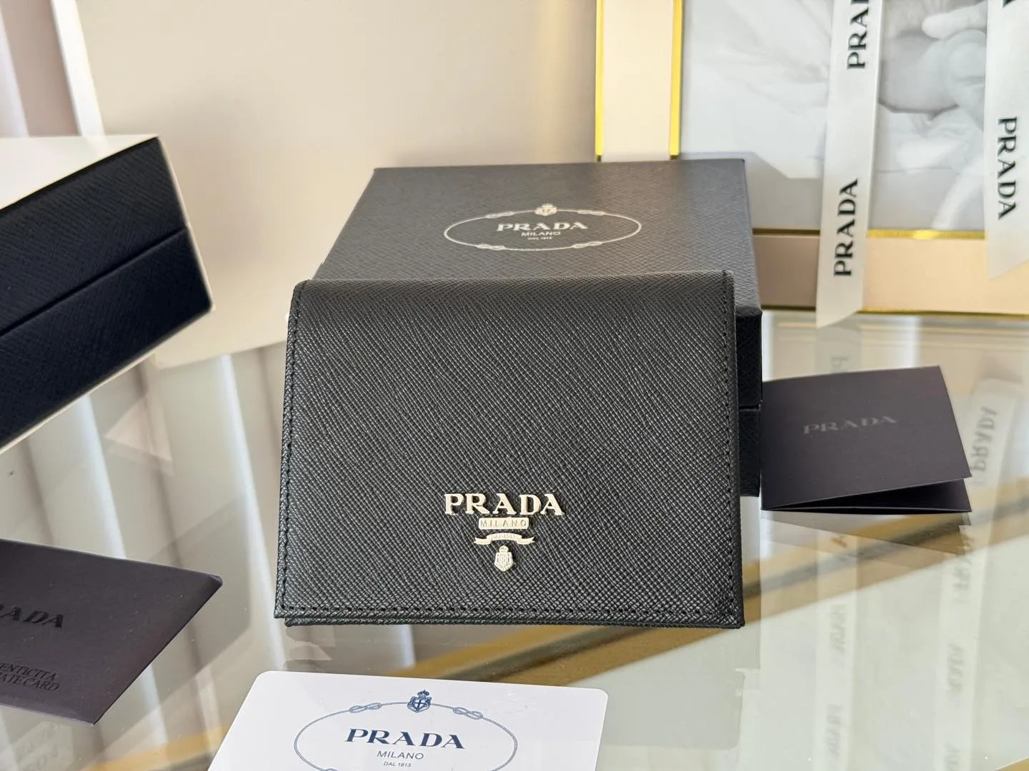 Prada women's two-fold short clip, with coin pocket and coin pocket. Model 1M0204, cross-grain cowhide. Size: 11.2x9.5cm. Simple and practical to enhance personal taste.