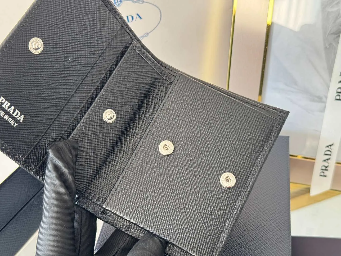 Prada women's two-fold short clip, with coin pocket and coin pocket. Model 1M0204, cross-grain cowhide. Size: 11.2x9.5cm. Simple and practical to enhance personal taste.