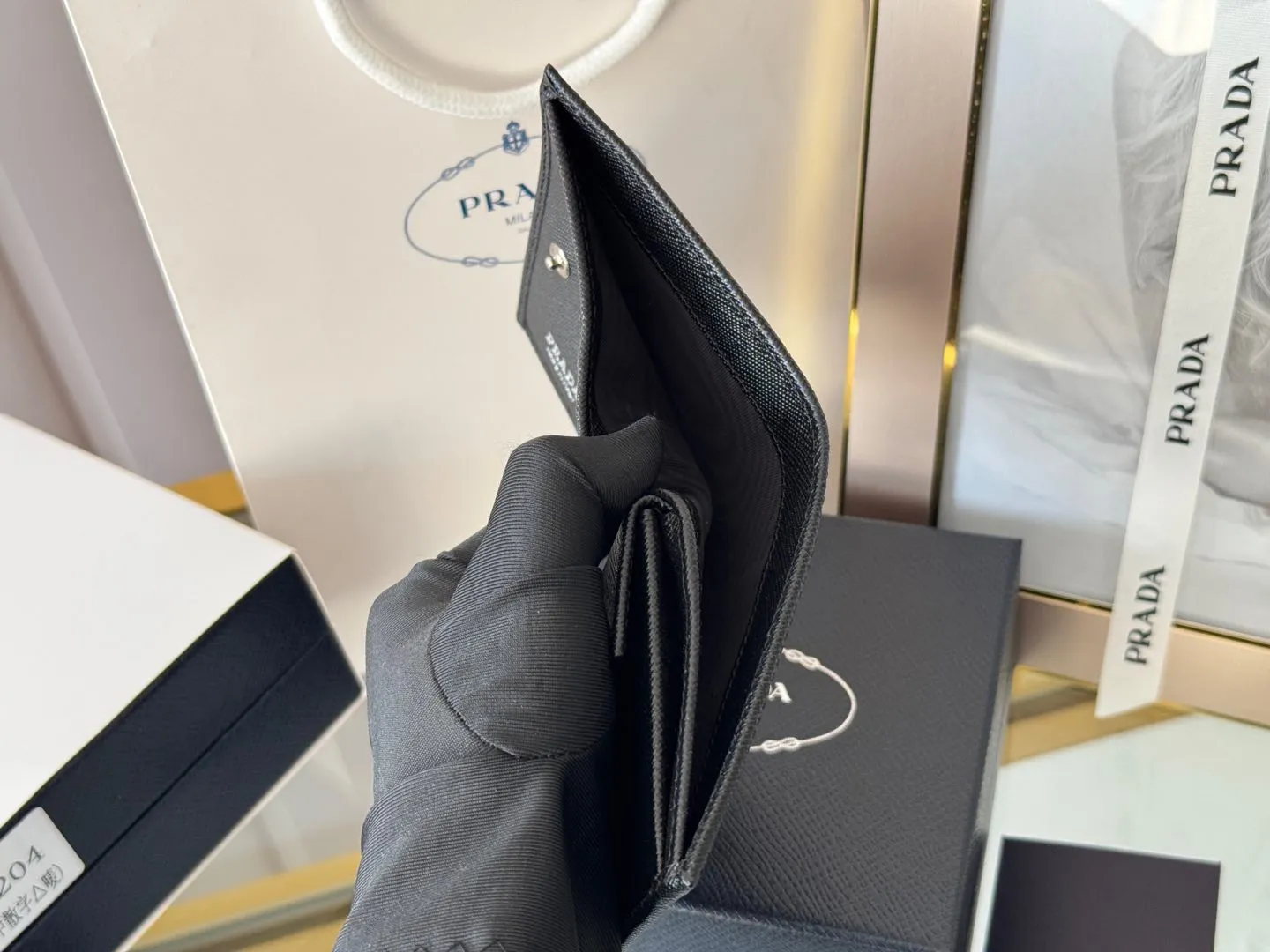 Prada women's two-fold short clip, with coin pocket and coin pocket. Model 1M0204, cross-grain cowhide. Size: 11.2x9.5cm. Simple and practical to enhance personal taste.