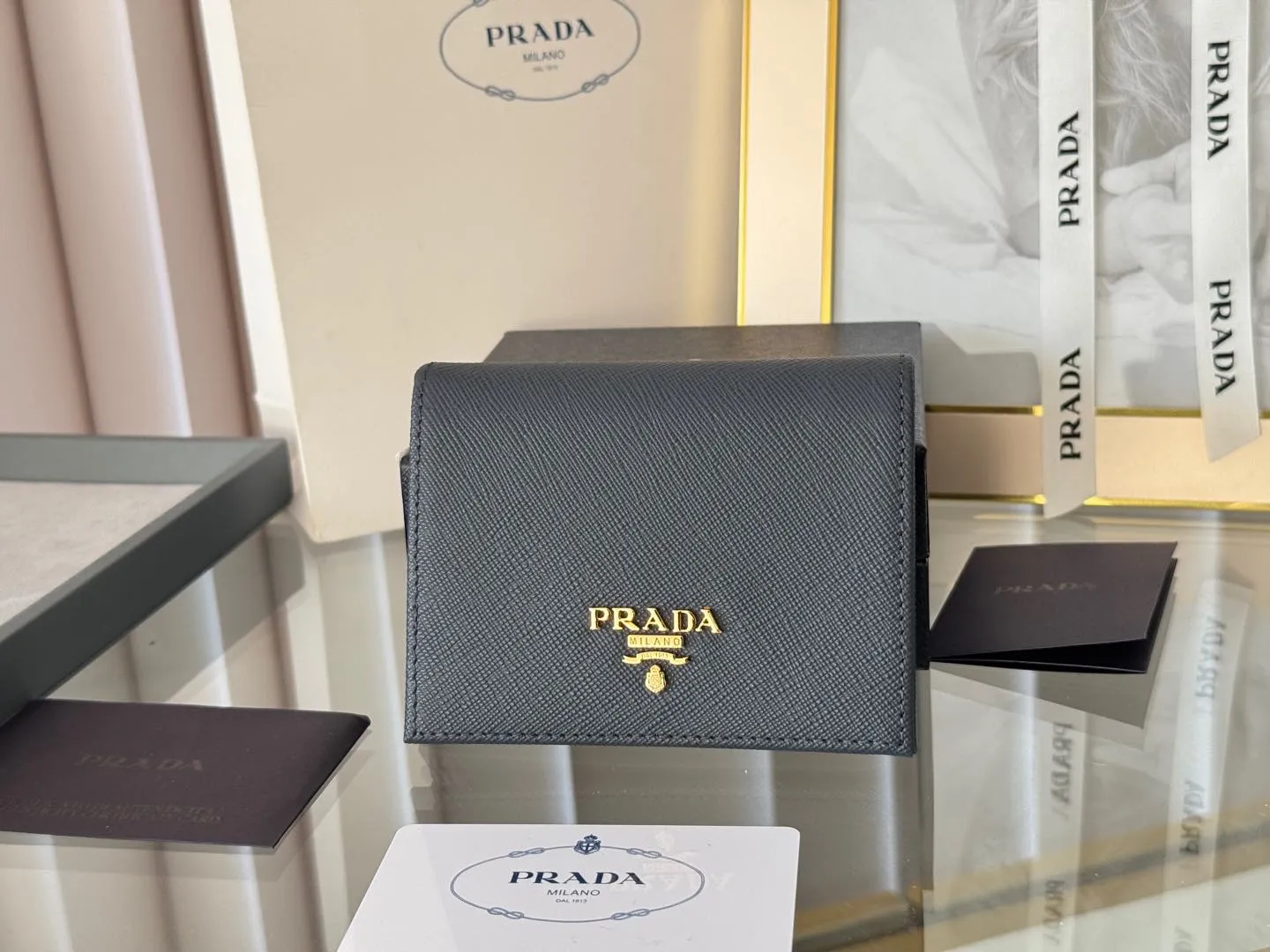 Prada women's two-fold short clip, with coin pocket and coin pocket. Model 1M0204, cross-grain cowhide. Size: 11.2x9.5cm. Simple and practical to enhance personal taste.