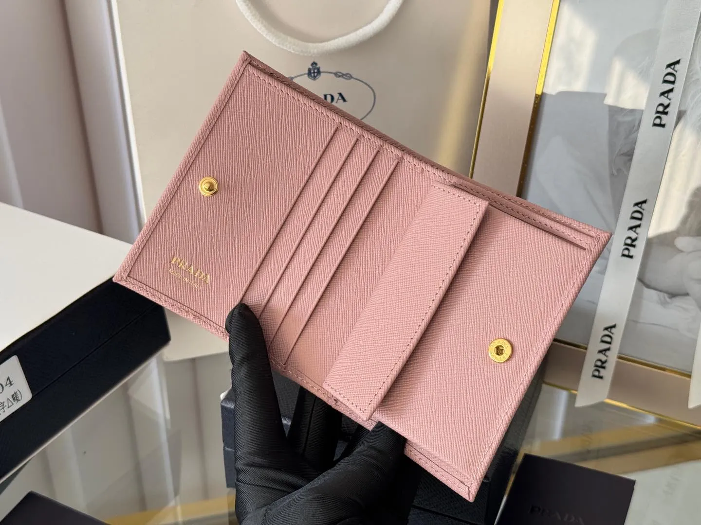 Prada women's two-fold short clip, with coin pocket and coin pocket. Model 1M0204, cross-grain cowhide. Size: 11.2x9.5cm. Simple and practical to enhance personal taste.