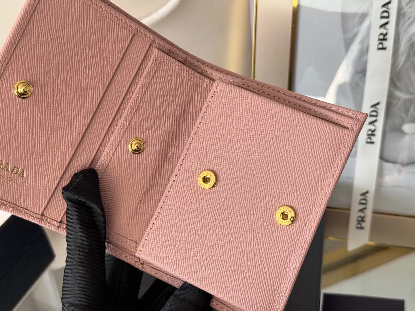 Prada women's two-fold short clip, with coin pocket and coin pocket. Model 1M0204, cross-grain cowhide. Size: 11.2x9.5cm. Simple and practical to enhance personal taste.