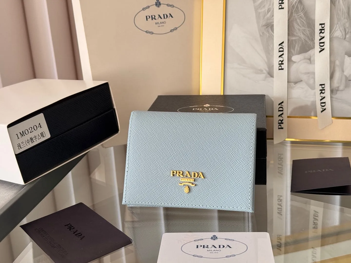 Prada women's two-fold short clip, with coin pocket and coin pocket. Model 1M0204, cross-grain cowhide. Size: 11.2x9.5cm. Simple and practical to enhance personal taste.