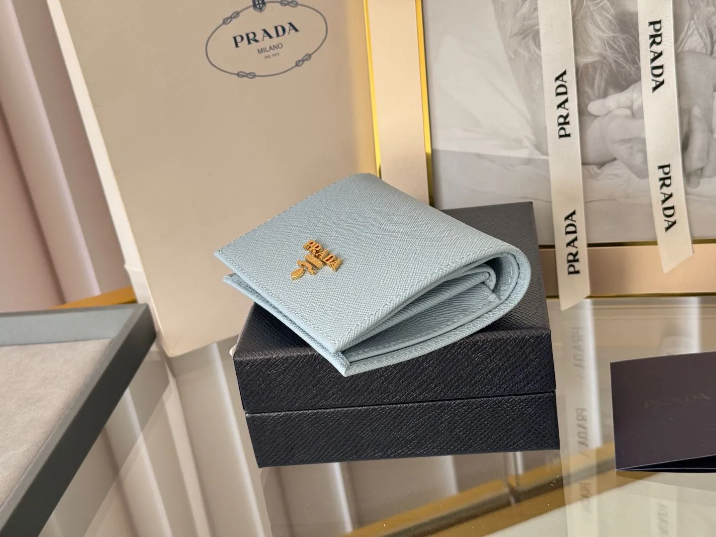 Prada women's two-fold short clip, with coin pocket and coin pocket. Model 1M0204, cross-grain cowhide. Size: 11.2x9.5cm. Simple and practical to enhance personal taste.