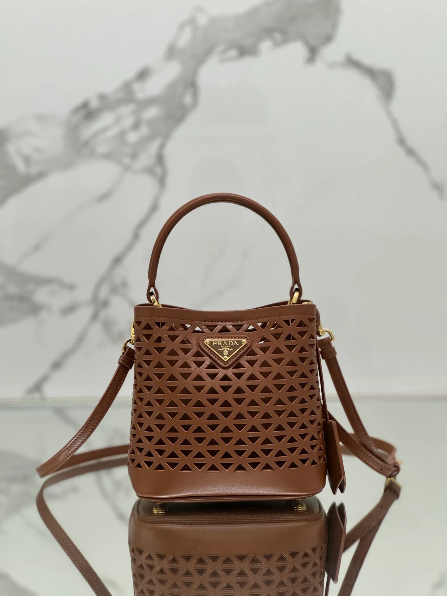 💰1640🌟Hollowout🐮Leather bucket bag The popular "elf" Saffiano perforated calfskin gives this P bucket bag a unique charm. The shape is not too soft and lacks spirit, nor is it too dull and lacks texture. The cute mini size adds a sense of fashion. It can be carried in hand, shoulder or crossbody. It is a handbag that perfectly integrates classic heritage and the trend of the times. Size: 18×17×10.5 cm Style number: 1BA217
