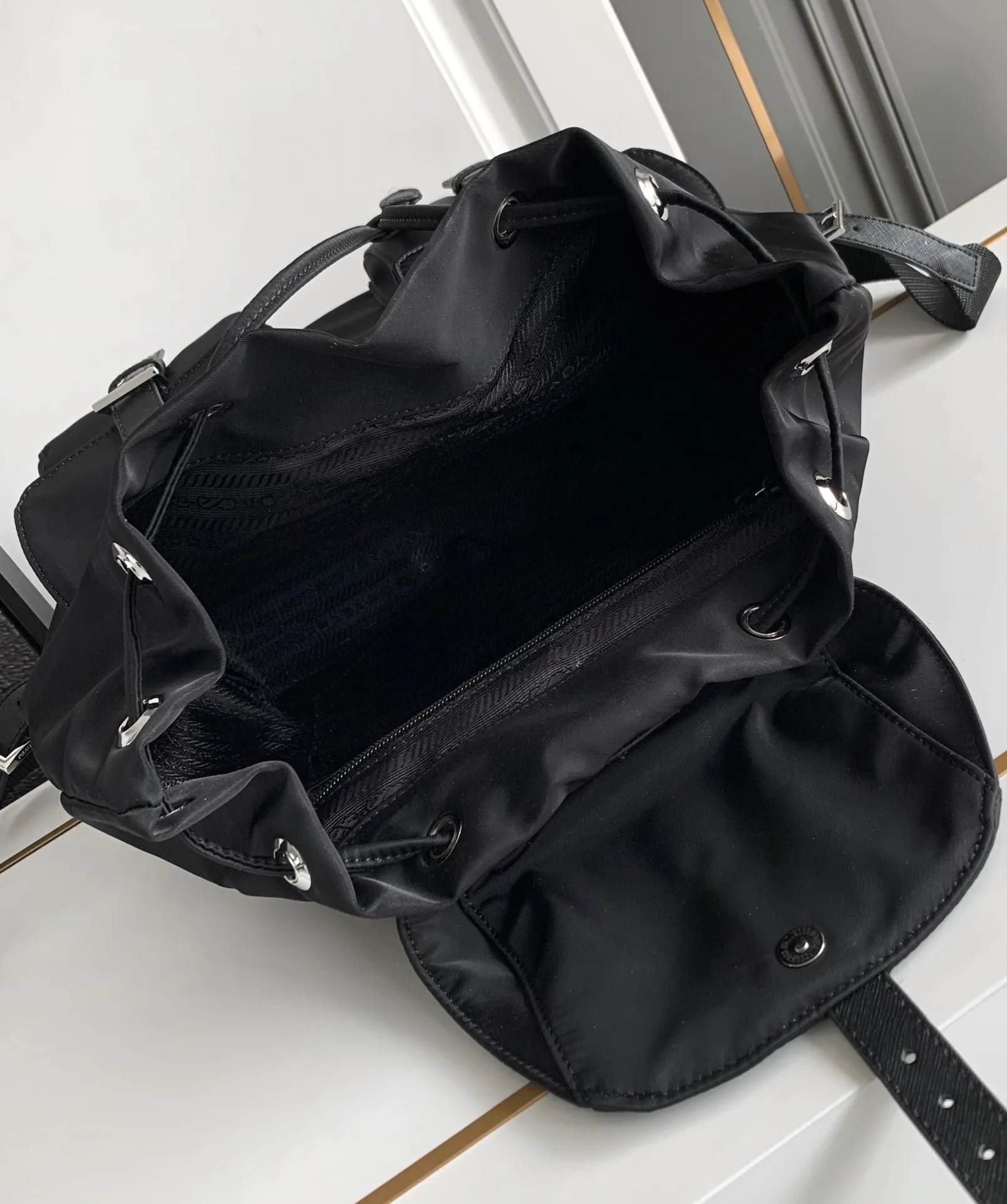 P640¥PR@DA 1BZ811 Nylon backpack is the most classic, best-selling and most versatile backpack of the P family. It is the first nylon bag designed by the chief founder himself. It is lightweight, rainproof, has a moderate capacity and is suitable for travel. It is matched with imported parachute fabric - waterproof and sunproof. Triangular enamel logo on the front, cross pattern cowhide trim. The overall style is fashionable and casual, yet stable and dignified. It has a large capacity to hold a kettle, iPad, mobile phone, books and documents. The drawstring inner bag + the two front zipper outer pockets meet the exquisite storage needs [Celebration]: 32*30*15cm black