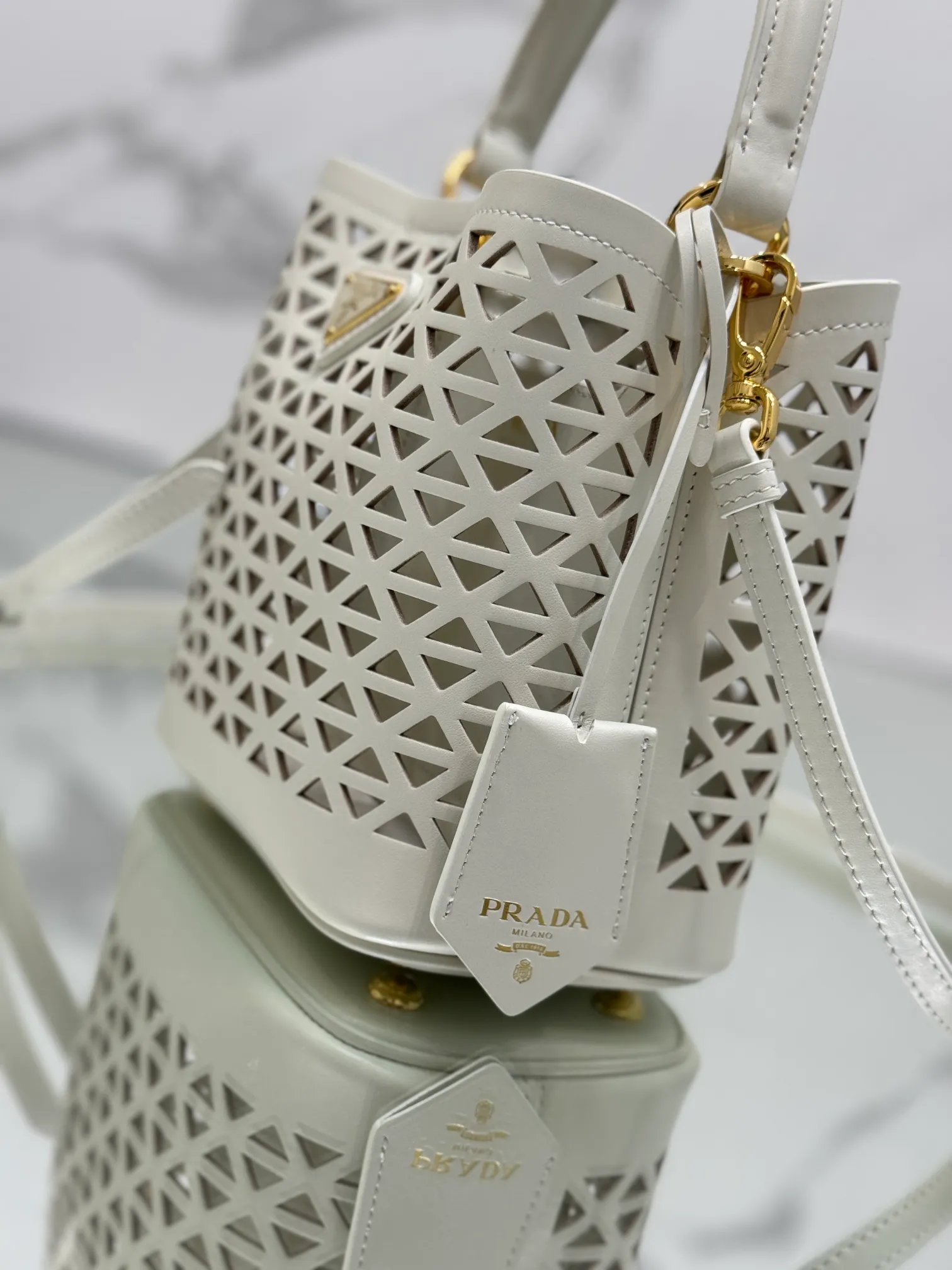 💰1640🌟Hollowout🐮Leather bucket bag The popular "elf" Saffiano perforated calfskin gives this P bucket bag a unique charm. The shape is not too soft and lacks spirit, nor is it too dull and lacks texture. The cute mini size adds a sense of fashion. It can be carried in hand, shoulder or crossbody. It is a handbag that perfectly integrates classic heritage and the trend of the times. Size: 18×17×10.5 cm Style number: 1BA217