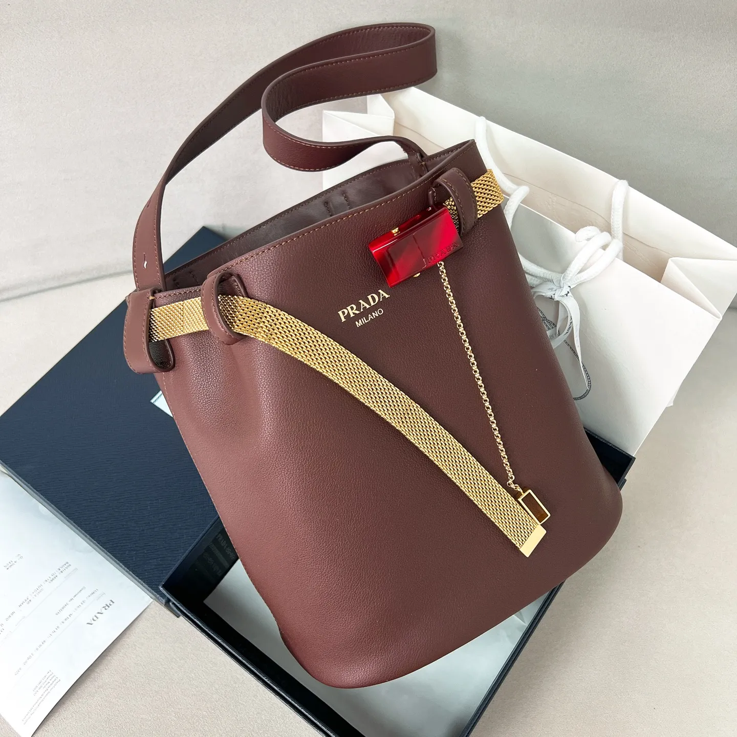 💰1700✨New product launch✨2025 spring and summer new product Buckle bucket bag 1BE085 inherits the classic bucket bag shape. The newly designed leather belt has a unique style that makes the bag infinitely dynamic. It is made of chic and noble calfskin. The bag is decorated with metallic mesh design. It is equipped with tortoise shell panel buckle. Elegant and simple bag body design is decorated with unique hardware decoration, showing a refined and elegant aesthetic style. Equipped with an adjustable hand strap, perfect details comparable to brick cabinets, super awesome 5🌟 size: 29*26.5*18cm, heather wood color