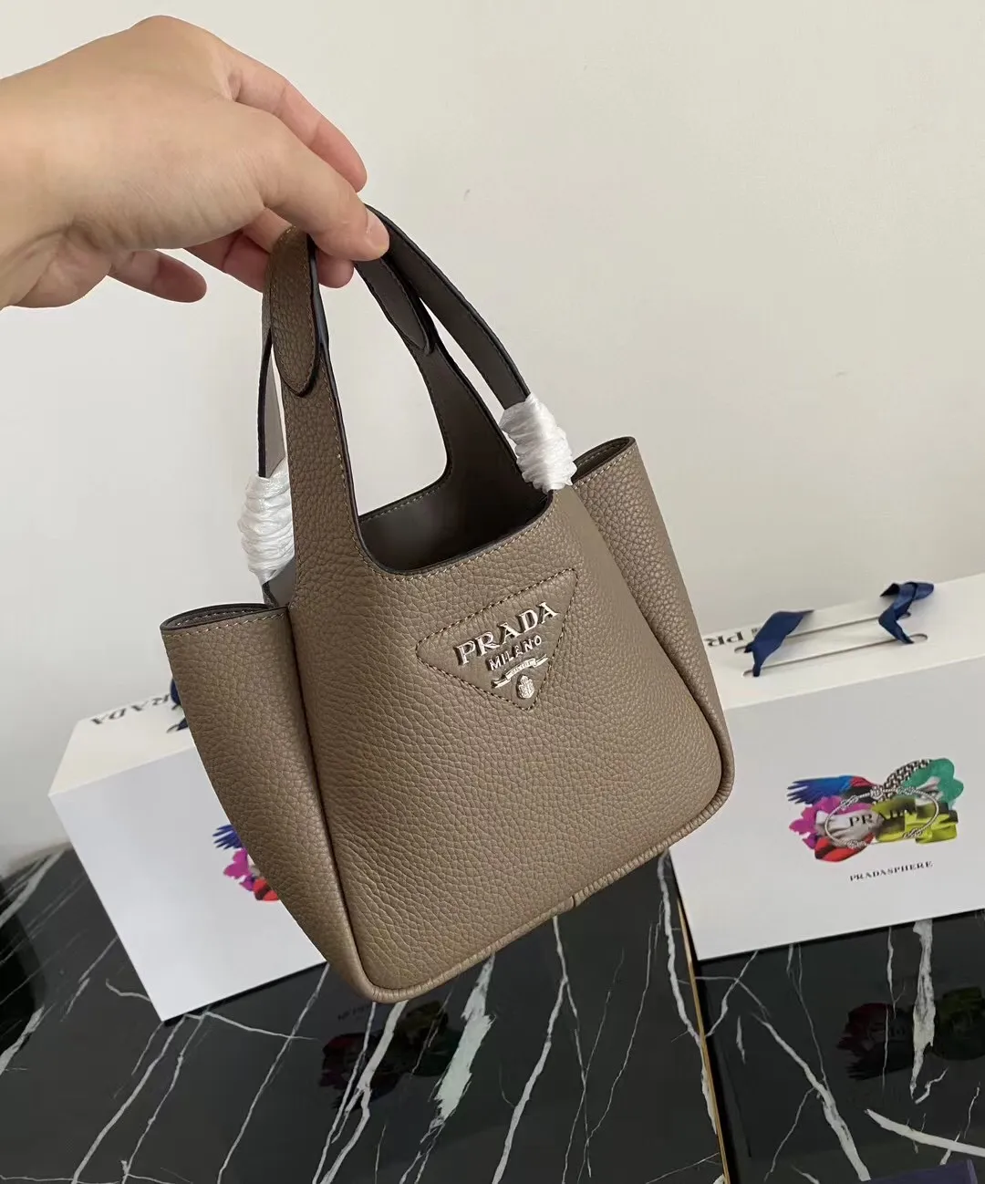 P1100¥ [Top original order] The latest 2022 vegetable basket tote bag mini model 1BA349 has arrived🎉🎉Soft and delicate pebbled calfskin tote bag, full leather inside and outside, equipped with double handles, decorated with silver metal logo, the overall body of the bag is very soft Lightweight, elegant and outstanding. The two side pockets not only meet the needs of exquisite storage but also add an elegant charm. It can be carried as a handbag or an armpit bag. It is a must-have handbag for fairies that perfectly combines classic heritage with the trend of the times. Size: 18︸15.5︸10CM!
