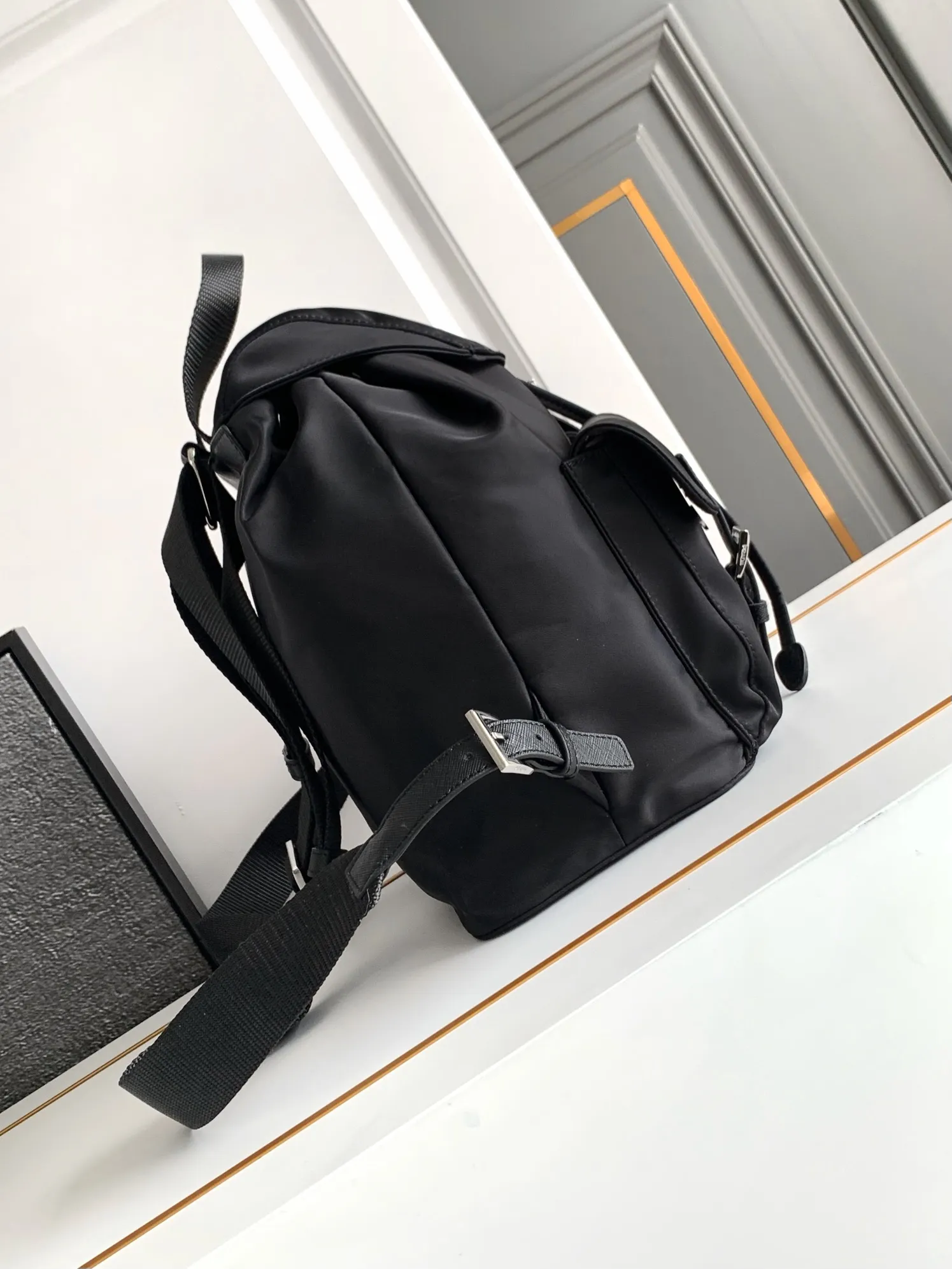 P640¥PR@DA 1BZ811 Nylon backpack is the most classic, best-selling and most versatile backpack of the P family. It is the first nylon bag designed by the chief founder himself. It is lightweight, rainproof, has a moderate capacity and is suitable for travel. It is matched with imported parachute fabric - waterproof and sunproof. Triangular enamel logo on the front, cross pattern cowhide trim. The overall style is fashionable and casual, yet stable and dignified. It has a large capacity to hold a kettle, iPad, mobile phone, books and documents. The drawstring inner bag + the two front zipper outer pockets meet the exquisite storage needs [Celebration]: 32*30*15cm black