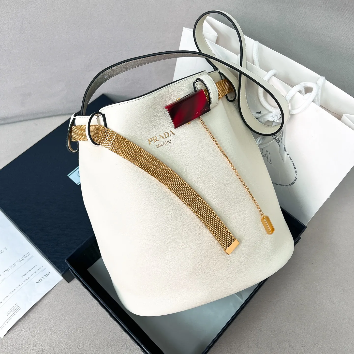 💰1700✨New product launch✨2025 spring and summer new product Buckle bucket bag 1BE085 inherits the classic bucket bag shape. The newly designed leather belt has a unique style that makes the bag infinitely dynamic. It is made of chic and noble calfskin. The bag is decorated with metallic mesh design. It is equipped with tortoise shell panel buckle. Elegant and simple bag body design is decorated with unique hardware decoration, showing a refined and elegant aesthetic style. Equipped with an adjustable hand strap, perfect details comparable to brick cabinets, super awesome 5🌟 size: 29*26.5*18cm white