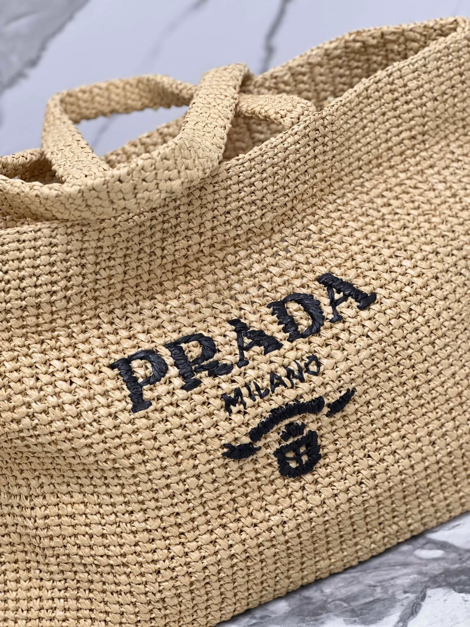 💰1900🌟Woven Tote Bag (Large Size) This tote bag is made of lightweight natural raffia fiber that is full of summer style. The soft deconstructed design gives the bag a unique modern charm. The iconic Prada lettering logo embroidery on the front subtly embellishes the silhouette. The striped pattern adds a contrasting element. So summery! Very versatile for everyday use. Size: length 40cm×height 34×width 15cm Style number: 1BG392