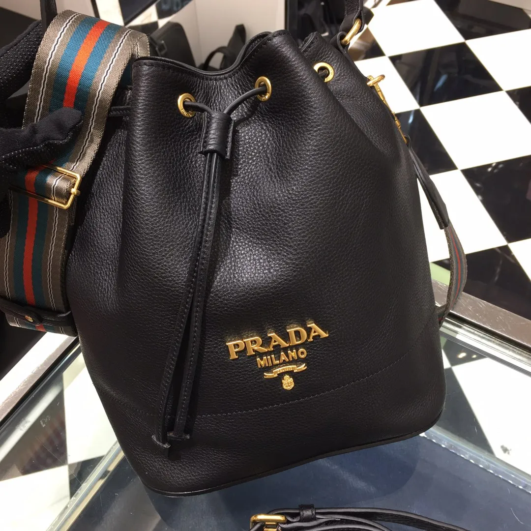 💰1660, P family has another popular bucket bag👏🏻👏🏻1BE018, the latest/most popular bucket bag🤙🤙Made of imported calfskin deerskin grain material, leather handle/2 replacement shoulder straps👏🏻👏🏻Detachable and adjustable colorful fabric shoulder straps, equipped with leather shoulder pads, metal lettering logo The top is decorated with a leather drawstring and is lined with a logo. There is a leather pocket inside, a large capacity and beautiful style🙋🏻🙋🏻, length 21x height 25x bottom 15cm.🤙