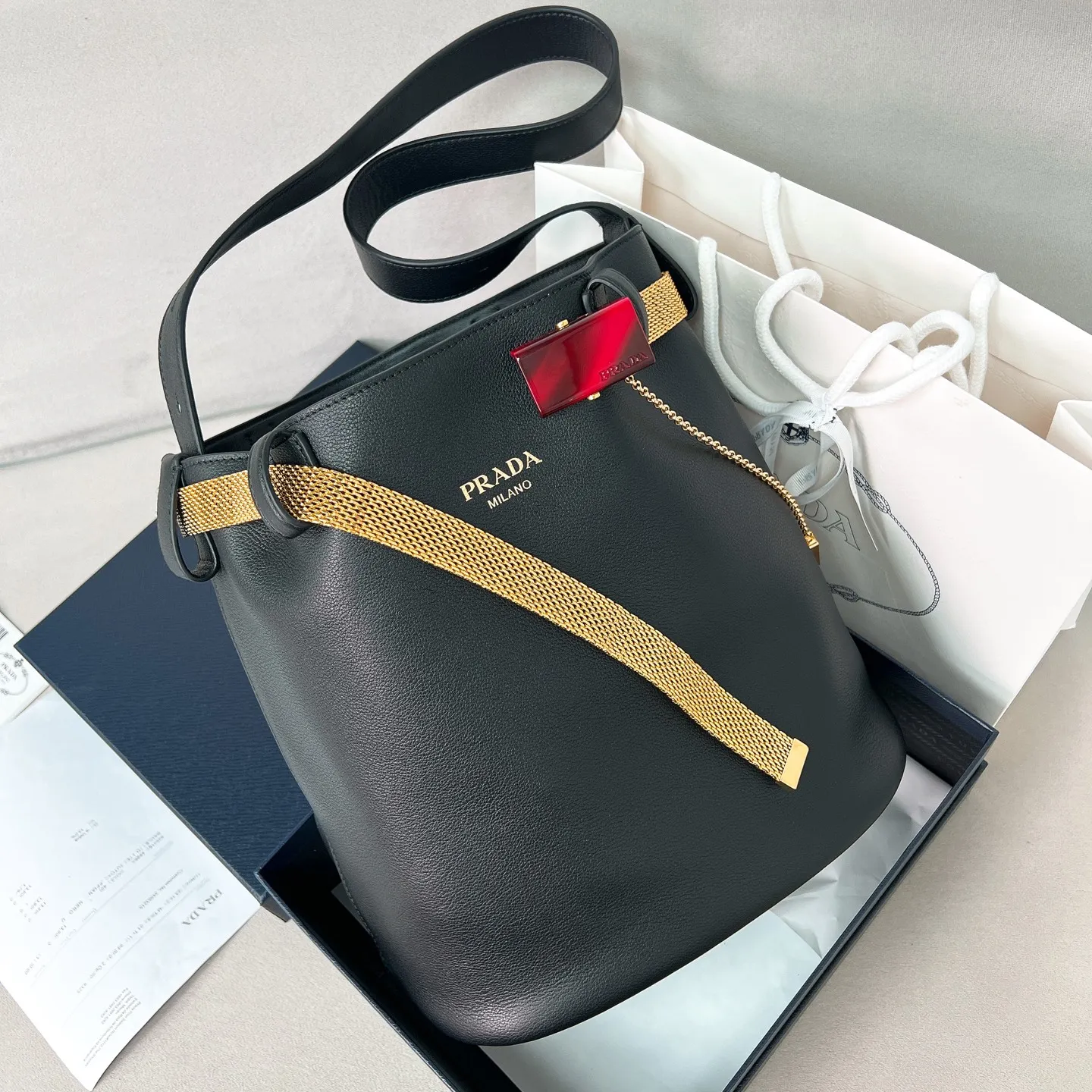 💰1700✨New product launch✨2025 spring and summer new product Buckle bucket bag 1BE085 inherits the classic bucket bag shape. The newly designed leather belt has a unique style that makes the bag infinitely dynamic. It is made of chic and noble calfskin. The bag is decorated with metallic mesh design. It is equipped with tortoise shell panel buckle. Elegant and simple bag body design is decorated with unique hardware decoration, showing a refined and elegant aesthetic style. Equipped with an adjustable hand strap, perfect details comparable to brick cabinets, super awesome 5🌟 size: 29*26.5*18cm black