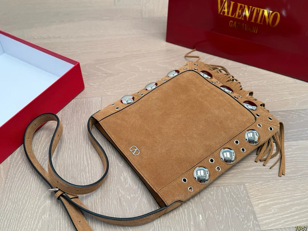 ¥330 with box Valentino tassel rivet handbag The tassel embellishment is super personalized! The V-shaped logo on the front is super classic and highly recognizable. The shoulder strap is adjustable, so it can be carried by hand or carried on the shoulder. It has a large capacity and can hold daily small items for commuting and traveling. The rivets and tassel design make the bag more layered, and it looks great with simple or retro styles. It is practical and fashionable, and can easily enhance the quality of your outfit! Size 29*30