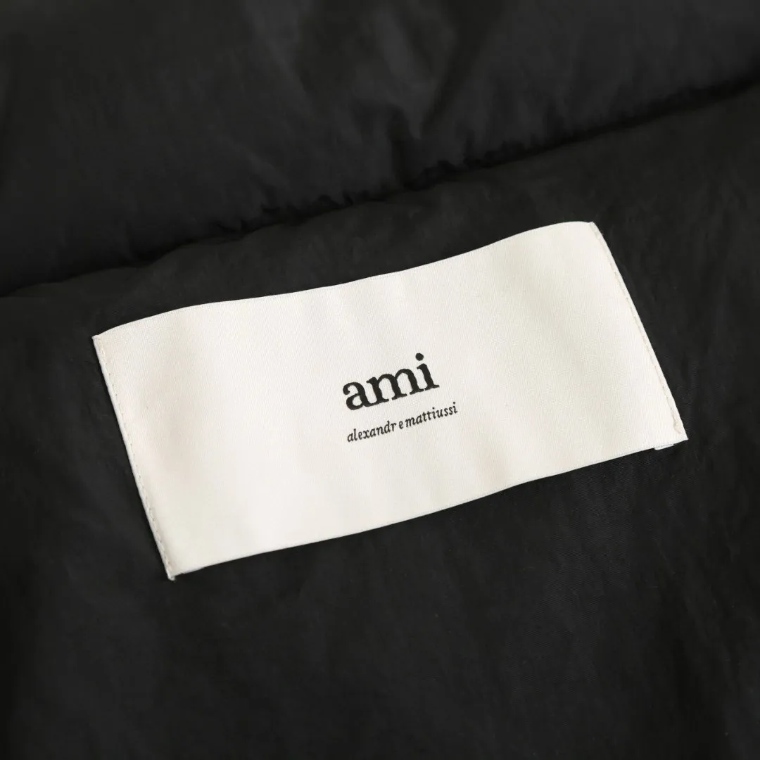 🅿️1000 [Exclusive supply] Ami love rubber stamp stand collar down jacket. The high-quality filling is made of 90 white duck down, which is full and even. The weight is 220g, ensuring good thermal insulation performance. The fabric is woven from 100% nylon. Its high-density structure achieves excellent windproof effect. It also has strong wear resistance and wrinkle resistance. It is scratch-free and easy to care for in daily wear. AMI's iconic love leather label is inlaid on the left chest using a 3D three-dimensional embossing process - the matte black cowhide is hand-polished to a thickness of 0.3mm, with micro-arc processing on the edges, making it as delicate to the touch as a baby's skin. The brand's iconic symbol is cleverly integrated into the center of the heart-shaped silhouette, becoming the only visual focus of the all-black body, low-key yet recognizable. The cuffs are equipped with high-density ribbing, made of 80-count combed cotton and spandex blend, with an elastic recovery rate of 95%. The rib edges are rolled by hand, and the thickness is only 0.5cm, but it can fit the wrist tightly, preventing cold wind from pouring in, and avoiding the bloated feeling of traditional down jacket cuffs. When you raise your hand, the ribs stretch naturally with your movements without feeling tight; when you are still, they return to their original shape, maintaining a neat silhouette, and the details highlight the "symbiosis of comfort and aesthetics." The body is three-dimensional quilted, and the quilting thread is made of high-elastic nylon thread, which is treated with the same color as the fabric. When viewed from a distance, the body of the garment looks like a whole piece of black velvet. Only when you look closer can you see the architectural layers outlined by the quilting thread. Size:S-M-L-XL