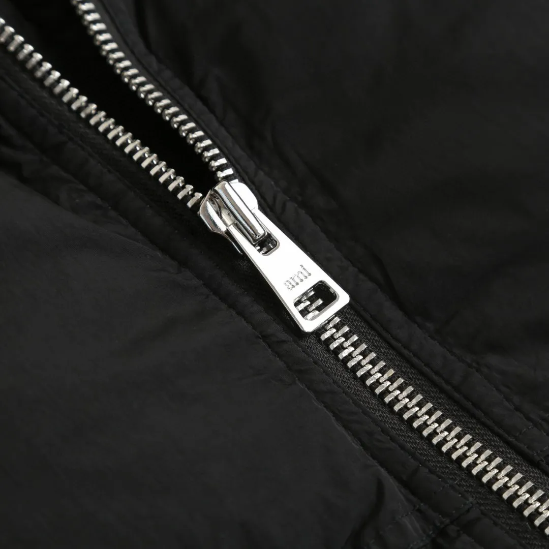 🅿️1000 [Exclusive supply] Ami love rubber stamp stand collar down jacket. The high-quality filling is made of 90 white duck down, which is full and even. The weight is 220g, ensuring good thermal insulation performance. The fabric is woven from 100% nylon. Its high-density structure achieves excellent windproof effect. It also has strong wear resistance and wrinkle resistance. It is scratch-free and easy to care for in daily wear. AMI's iconic love leather label is inlaid on the left chest using a 3D three-dimensional embossing process - the matte black cowhide is hand-polished to a thickness of 0.3mm, with micro-arc processing on the edges, making it as delicate to the touch as a baby's skin. The brand's iconic symbol is cleverly integrated into the center of the heart-shaped silhouette, becoming the only visual focus of the all-black body, low-key yet recognizable. The cuffs are equipped with high-density ribbing, made of 80-count combed cotton and spandex blend, with an elastic recovery rate of 95%. The rib edges are rolled by hand, and the thickness is only 0.5cm, but it can fit the wrist tightly, preventing cold wind from pouring in, and avoiding the bloated feeling of traditional down jacket cuffs. When you raise your hand, the ribs stretch naturally with your movements without feeling tight; when you are still, they return to their original shape, maintaining a neat silhouette, and the details highlight the "symbiosis of comfort and aesthetics." The body is three-dimensional quilted, and the quilting thread is made of high-elastic nylon thread, which is treated with the same color as the fabric. When viewed from a distance, the body of the garment looks like a whole piece of black velvet. Only when you look closer can you see the architectural layers outlined by the quilting thread. Size:S-M-L-XL