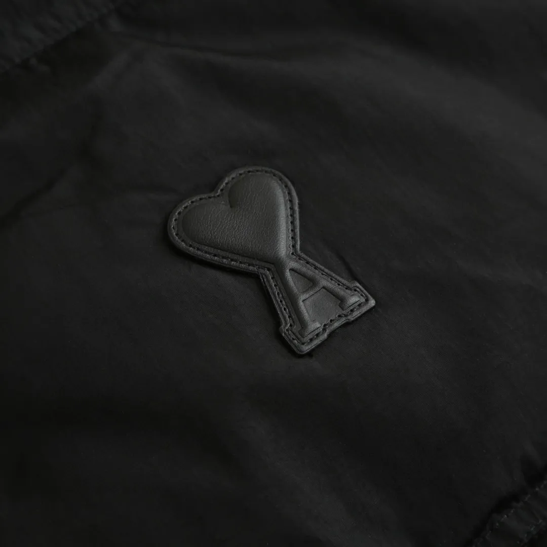 🅿️1000 [Exclusive supply] Ami love rubber stamp stand collar down jacket. The high-quality filling is made of 90 white duck down, which is full and even. The weight is 220g, ensuring good thermal insulation performance. The fabric is woven from 100% nylon. Its high-density structure achieves excellent windproof effect. It also has strong wear resistance and wrinkle resistance. It is scratch-free and easy to care for in daily wear. AMI's iconic love leather label is inlaid on the left chest using a 3D three-dimensional embossing process - the matte black cowhide is hand-polished to a thickness of 0.3mm, with micro-arc processing on the edges, making it as delicate to the touch as a baby's skin. The brand's iconic symbol is cleverly integrated into the center of the heart-shaped silhouette, becoming the only visual focus of the all-black body, low-key yet recognizable. The cuffs are equipped with high-density ribbing, made of 80-count combed cotton and spandex blend, with an elastic recovery rate of 95%. The rib edges are rolled by hand, and the thickness is only 0.5cm, but it can fit the wrist tightly, preventing cold wind from pouring in, and avoiding the bloated feeling of traditional down jacket cuffs. When you raise your hand, the ribs stretch naturally with your movements without feeling tight; when you are still, they return to their original shape, maintaining a neat silhouette, and the details highlight the "symbiosis of comfort and aesthetics." The body is three-dimensional quilted, and the quilting thread is made of high-elastic nylon thread, which is treated with the same color as the fabric. When viewed from a distance, the body of the garment looks like a whole piece of black velvet. Only when you look closer can you see the architectural layers outlined by the quilting thread. Size:S-M-L-XL
