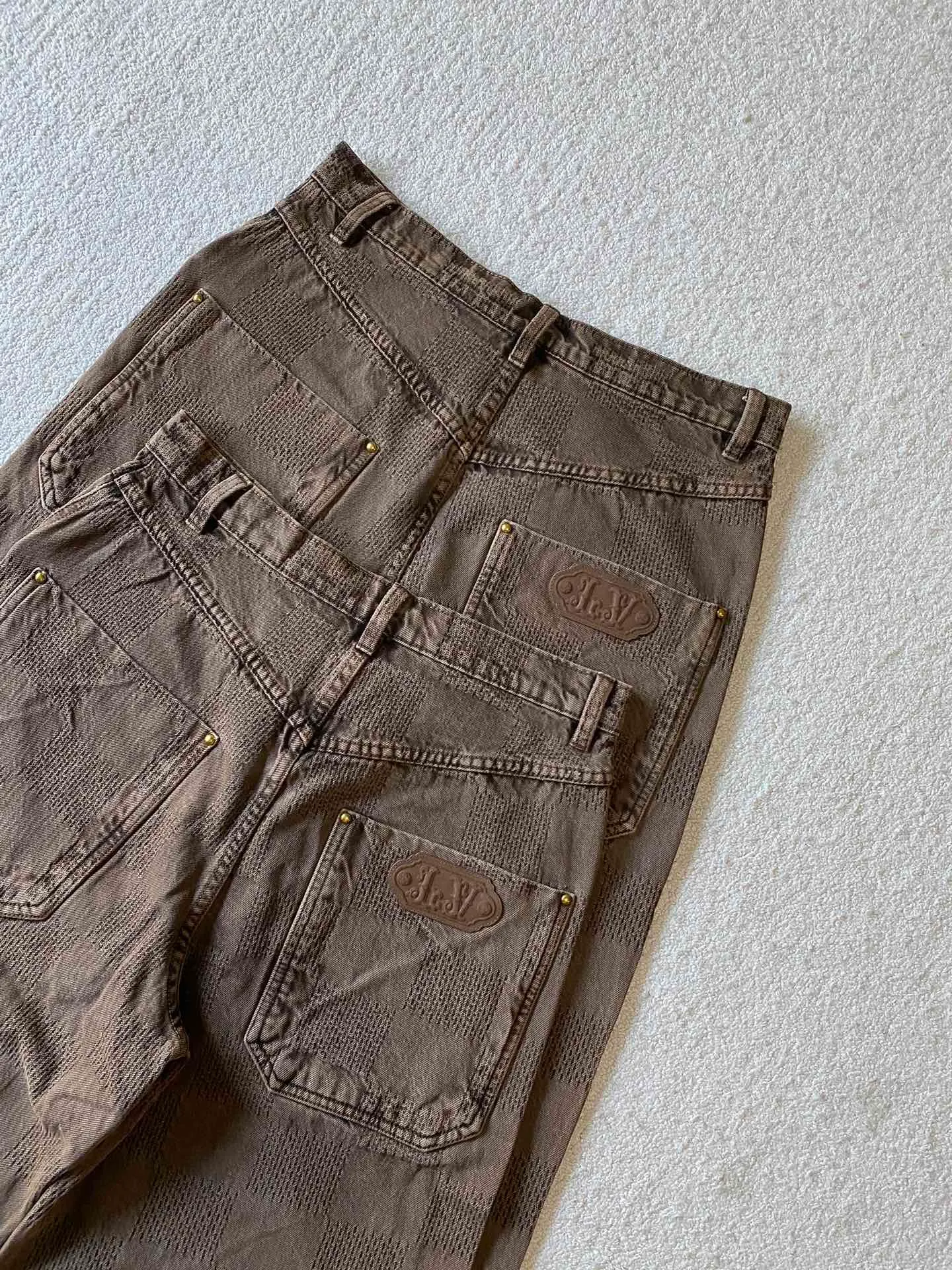LV brown checkerboard denim straight trousers ⚠️Original purchase, 600, skateboard straight version, Marque L. Uuitton deposee logo integrated into 3D Damier jacquard, back Damier label, sand washed distressed, topstitch sewing, placket distressed hardware closure #Logo integrated into 3D Damier jacquard 3D Damier jacquard denim fabric is an innovative fabric that combines jacquard technology and the characteristics of denim cloth. The classic plaid pattern is combined with 3D jacquard technology to weave three-dimensional patterns on the fabric through a loom.  The fabric presents an exquisite plaid pattern in appearance, and the pattern is made three-dimensional and layered through jacquard technology. At the same time, it retains the original tough, wear-resistant and durable properties of denim, making the clothes more durable.  # Sandwashed, Faded and Distressed Effect Sandwashed, faded and distressed denim fabric is a specially treated denim fabric that exhibits a whitened and distressed effect. This fabric uses a sand-washing process and special dyeing technology to create a natural wear and fading effect on the denim after washing, making it look more vintage and historical.  #skateboard straight jeans version Skateboard jeans are usually designed to be looser to accommodate the large movements and squatting postures during skateboarding. Jeans have a straight shape and a consistent width from hip to hem. Suitable for all body types, these straight-leg skateboard pants are designed with comfort and freedom in mind for skateboarding.