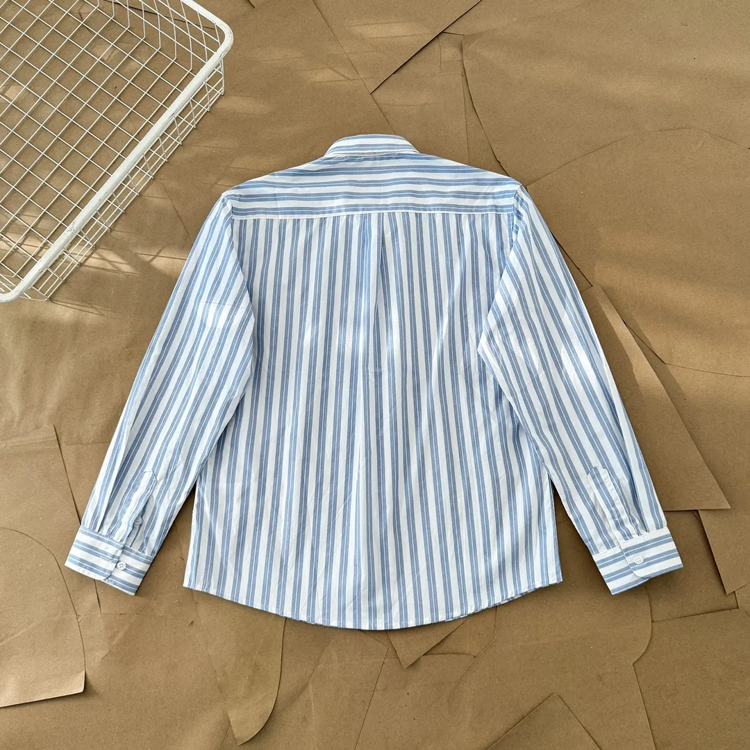 Ami Paris Oxford cotton button-down corner collar casual shirt-blue heart thick striped long-sleeved shirt-same style for men and women. Blue small love letter embroidery decoration fashionable and versatile long-sleeved shirt! On sale simultaneously at counters!  A well-known French affordable luxury fashion brand. The brand's classic elements are embellishments sought after by major celebrities. Its basic simple design and fashionable style make it a must-have couple's shirt for men and women!  Made of custom-woven 100% Oxford cloth pure cotton, it feels soft and delicate, has excellent moisture absorption and perspiration performance, and is very comfortable and skin-friendly when worn next to the skin! The chest of the shirt is decorated with the classic love letter A logo embroidery. The top-notch embroidery technology is tight, full and full of details, and is cleverly embellished with bright red. It carries all the eye-catching points. It follows the consistent minimalist French attitude. The fabric is soft and comfortable, suitable for any versatile casual shirt couple!  Color: Blue Stripe Size: S-XL S: Bust 106 Shoulder Width 47 Clothing Length 71 Sleeve Length 60 M: Bust 110 Shoulder Width 48 Clothing Length 73 Sleeve Length 61 L: Bust 114 Shoulder Width 49 Clothing Length 75 Sleeve Length 62