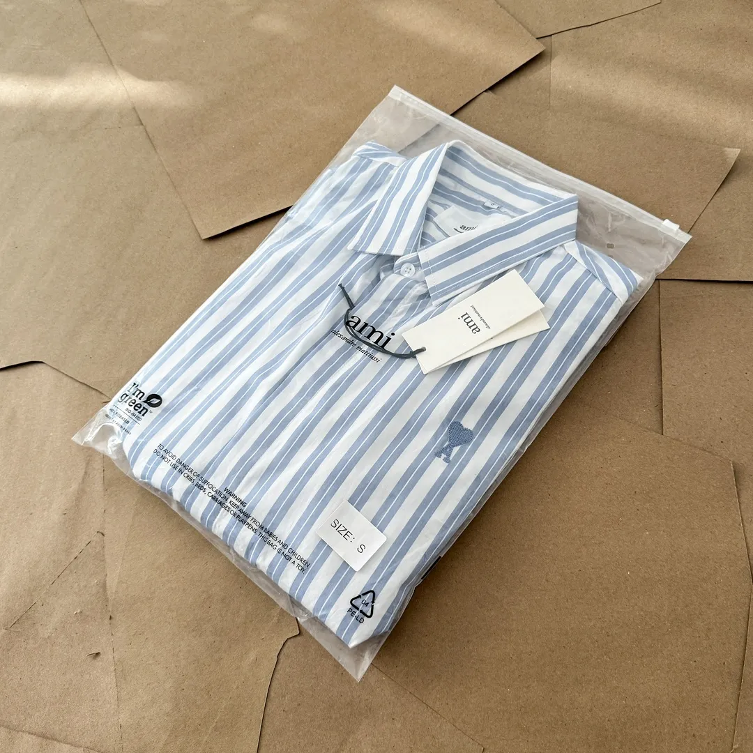 Ami Paris Oxford cotton button-down corner collar casual shirt-blue heart thick striped long-sleeved shirt-same style for men and women. Blue small love letter embroidery decoration fashionable and versatile long-sleeved shirt! On sale simultaneously at counters!  A well-known French affordable luxury fashion brand. The brand's classic elements are embellishments sought after by major celebrities. Its basic simple design and fashionable style make it a must-have couple's shirt for men and women!  Made of custom-woven 100% Oxford cloth pure cotton, it feels soft and delicate, has excellent moisture absorption and perspiration performance, and is very comfortable and skin-friendly when worn next to the skin! The chest of the shirt is decorated with the classic love letter A logo embroidery. The top-notch embroidery technology is tight, full and full of details, and is cleverly embellished with bright red. It carries all the eye-catching points. It follows the consistent minimalist French attitude. The fabric is soft and comfortable, suitable for any versatile casual shirt couple!  Color: Blue Stripe Size: S-XL S: Bust 106 Shoulder Width 47 Clothing Length 71 Sleeve Length 60 M: Bust 110 Shoulder Width 48 Clothing Length 73 Sleeve Length 61 L: Bust 114 Shoulder Width 49 Clothing Length 75 Sleeve Length 62