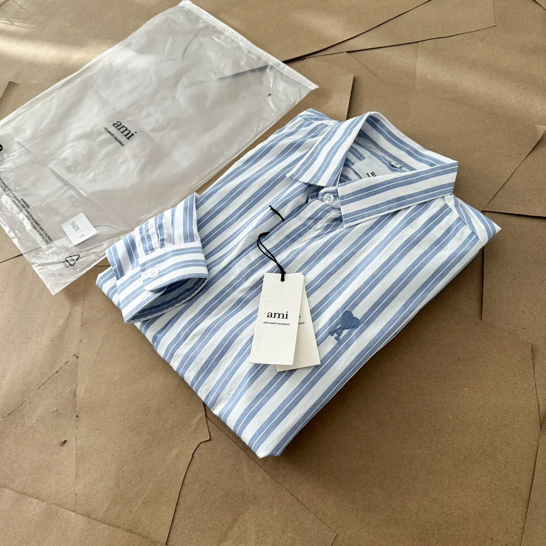 Ami Paris Oxford cotton button-down corner collar casual shirt-blue heart thick striped long-sleeved shirt-same style for men and women. Blue small love letter embroidery decoration fashionable and versatile long-sleeved shirt! On sale simultaneously at counters!  A well-known French affordable luxury fashion brand. The brand's classic elements are embellishments sought after by major celebrities. Its basic simple design and fashionable style make it a must-have couple's shirt for men and women!  Made of custom-woven 100% Oxford cloth pure cotton, it feels soft and delicate, has excellent moisture absorption and perspiration performance, and is very comfortable and skin-friendly when worn next to the skin! The chest of the shirt is decorated with the classic love letter A logo embroidery. The top-notch embroidery technology is tight, full and full of details, and is cleverly embellished with bright red. It carries all the eye-catching points. It follows the consistent minimalist French attitude. The fabric is soft and comfortable, suitable for any versatile casual shirt couple!  Color: Blue Stripe Size: S-XL S: Bust 106 Shoulder Width 47 Clothing Length 71 Sleeve Length 60 M: Bust 110 Shoulder Width 48 Clothing Length 73 Sleeve Length 61 L: Bust 114 Shoulder Width 49 Clothing Length 75 Sleeve Length 62