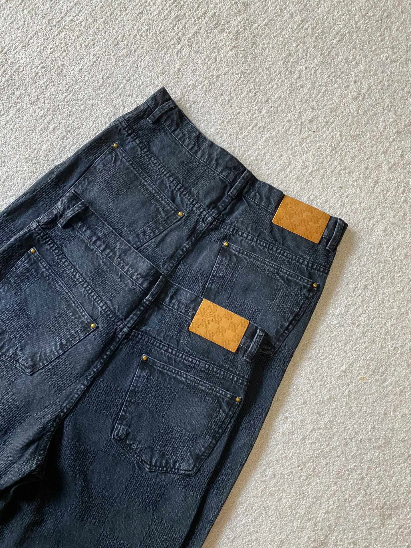 LU black checkerboard denim straight trousers ⚠️Original purchase, 600, skateboard straight version, Marque L. Uuitton deposee logo integrated into 3D Damier jacquard, back Damier label, sand washed distressed, topstitch sewing, placket distressed hardware closure #Logo integrated into 3D Damier jacquard 3D Damier jacquard denim fabric is an innovative fabric that combines jacquard technology and the characteristics of denim cloth. The classic plaid pattern is combined with 3D jacquard technology to weave three-dimensional patterns on the fabric through a loom.  The fabric presents an exquisite plaid pattern in appearance, and the pattern is made three-dimensional and layered through jacquard technology. At the same time, it retains the original tough, wear-resistant and durable properties of denim, making the clothes more durable.  # Sandwashed, Faded and Distressed Effect Sandwashed, faded and distressed denim fabric is a specially treated denim fabric that exhibits a whitened and distressed effect. This fabric uses a sand-washing process and special dyeing technology to create a natural wear and fading effect on the denim after washing, making it look more vintage and historical.  #skateboard straight jeans version Skateboard jeans are usually designed to be looser to accommodate the large movements and squatting postures during skateboarding. Jeans have a straight shape and a consistent width from hip to hem. Suitable for all body types, these straight-leg skateboard pants are designed with comfort and freedom in mind for skateboarding.
