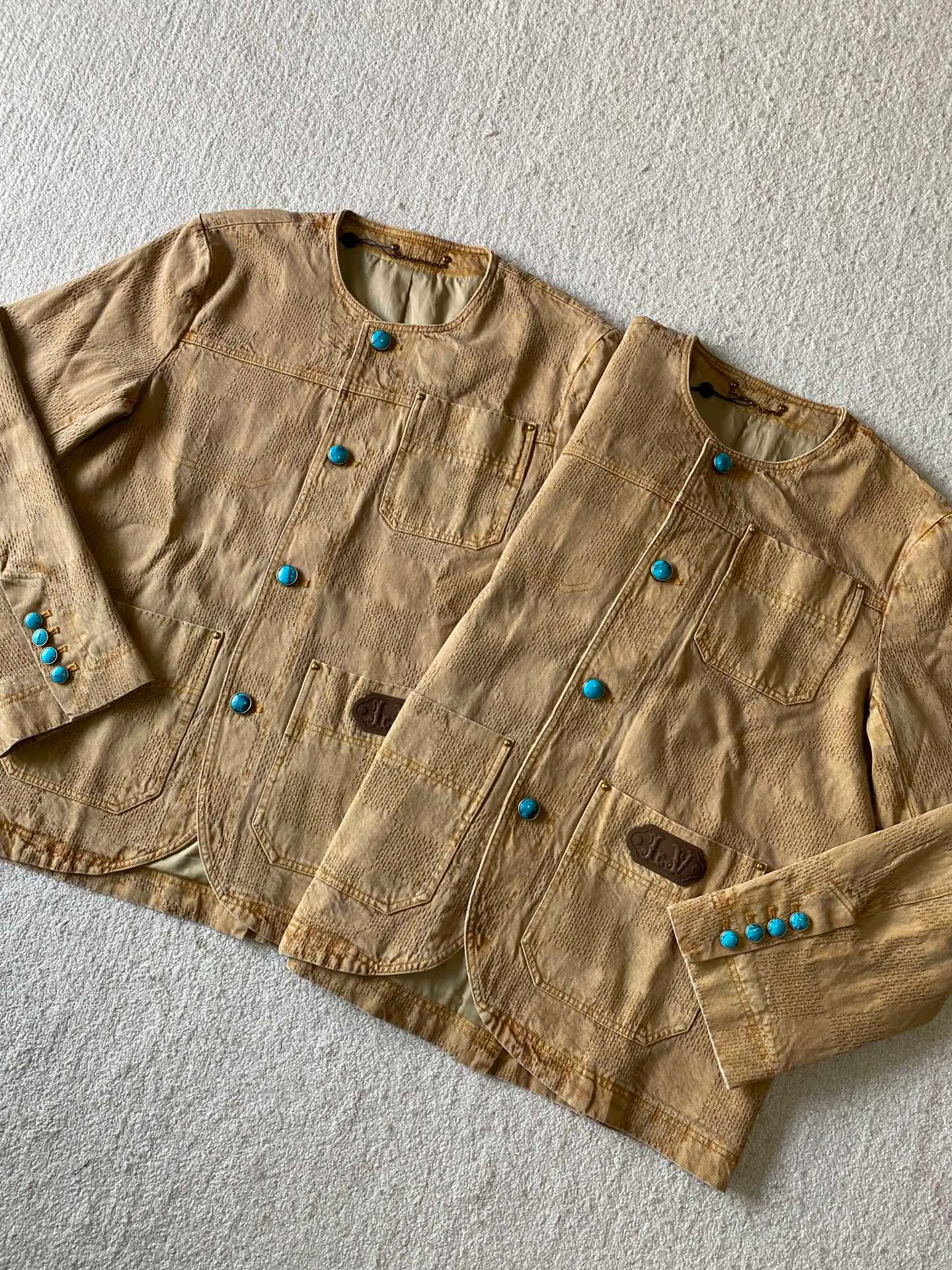 LV saddle checkerboard denim suit • Jacket ⚠️Original purchase, 000; standard fit, checkerboard element jacquard, lower left pocket embellished with Saddle patch, collarless curved hem, front patch pockets including chest pockets, hand-stitched button details, new button series buttons exclusively developed #logo integrated into 3D Damier jacquard 3D Damier jacquard denim fabric is an innovative fabric that combines jacquard technology and the characteristics of denim. The classic plaid pattern is combined with 3D jacquard technology to weave three-dimensional patterns on the fabric through a loom.  The fabric presents an exquisite plaid pattern in appearance, and the pattern is made three-dimensional and layered through jacquard technology. At the same time, it retains the original tough, wear-resistant and durable properties of denim, making the clothes more durable.  #Grey cloth retro coloring process is a process that uses a specific process to make the originally white denim show a retro, worn-out special color effect. Clean the white denim fabric to remove surface impurities and residues. Through specific processing methods, the fabric can maintain stable dimensions during subsequent processing.  Choose the appropriate natural dye for the desired distressing effect on the plate. The dye is evenly applied to the fabric, giving it a gradient coloring effect. After dyeing is completed, necessary cleaning and color fixing treatments are required to ensure color stability and durability.  # Sandwashed, Faded and Distressed Effect Sandwashed, faded and distressed denim fabric is a specially treated denim fabric that exhibits a whitened and distressed effect. This fabric uses a sand-washing process and special dyeing technology to create a natural wear and fading effect on the denim after washing, making it look more vintage and historical.  # Collarless curved hem shirt version Collarless curved hem denim shirt version is a unique and fashionable clothing design. The entire shirt style looks simpler and lighter. There is no traditional collar, focusing more on comfort and freedom; the curved hem fits the body curve better. Balance the visual effect of the entire shirt and make it look more harmonious and unified.  Opposite patch pocket design; door sills are opened and closed with new hand-stitched phantom sapphire buttons; cuffs are decorated with matching embellishments; a full set of molded custom hardware with clear and delicate gem surface engravings and environmentally friendly plating; basic accessories are fully equipped.