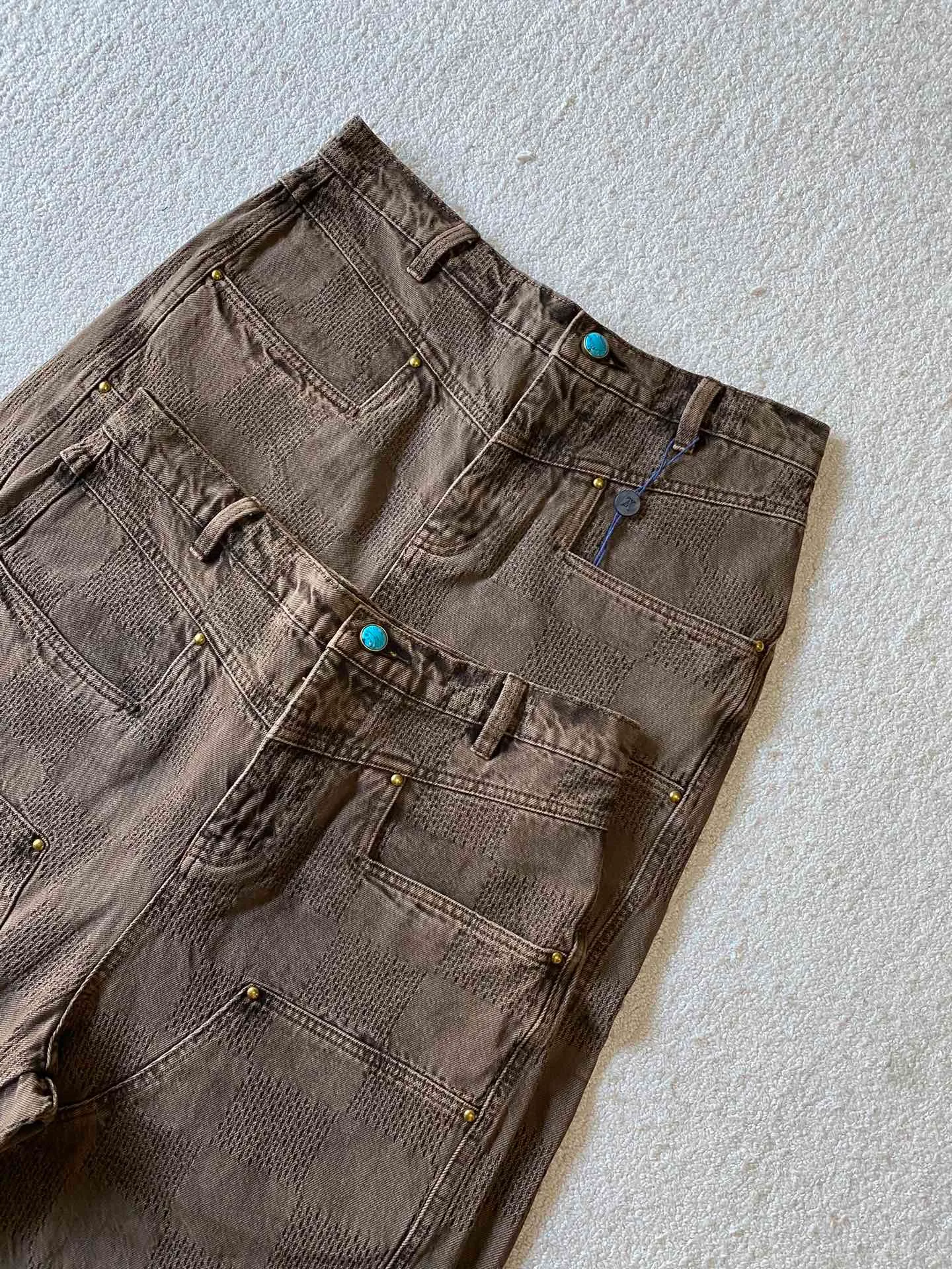 LU brown checkerboard denim straight trousers ⚠️Original purchase, 600, skateboard straight version, Marque L. Uuitton deposee logo integrated into 3D Damier jacquard, back Damier label, sand washed distressed, topstitch sewing, placket distressed hardware closure #Logo integrated into 3D Damier jacquard 3D Damier jacquard denim fabric is an innovative fabric that combines jacquard technology and the characteristics of denim cloth. The classic plaid pattern is combined with 3D jacquard technology to weave three-dimensional patterns on the fabric through a loom.  The fabric presents an exquisite plaid pattern in appearance, and the pattern is made three-dimensional and layered through jacquard technology. At the same time, it retains the original tough, wear-resistant and durable properties of denim, making the clothes more durable.  # Sandwashed, Faded and Distressed Effect Sandwashed, faded and distressed denim fabric is a specially treated denim fabric that exhibits a whitened and distressed effect. This fabric uses a sand-washing process and special dyeing technology to create a natural wear and fading effect on the denim after washing, making it look more vintage and historical.  #skateboard straight jeans version Skateboard jeans are usually designed to be looser to accommodate the large movements and squatting postures during skateboarding. Jeans have a straight shape and a consistent width from hip to hem. Suitable for all body types, these straight-leg skateboard pants are designed with comfort and freedom in mind for skateboarding.