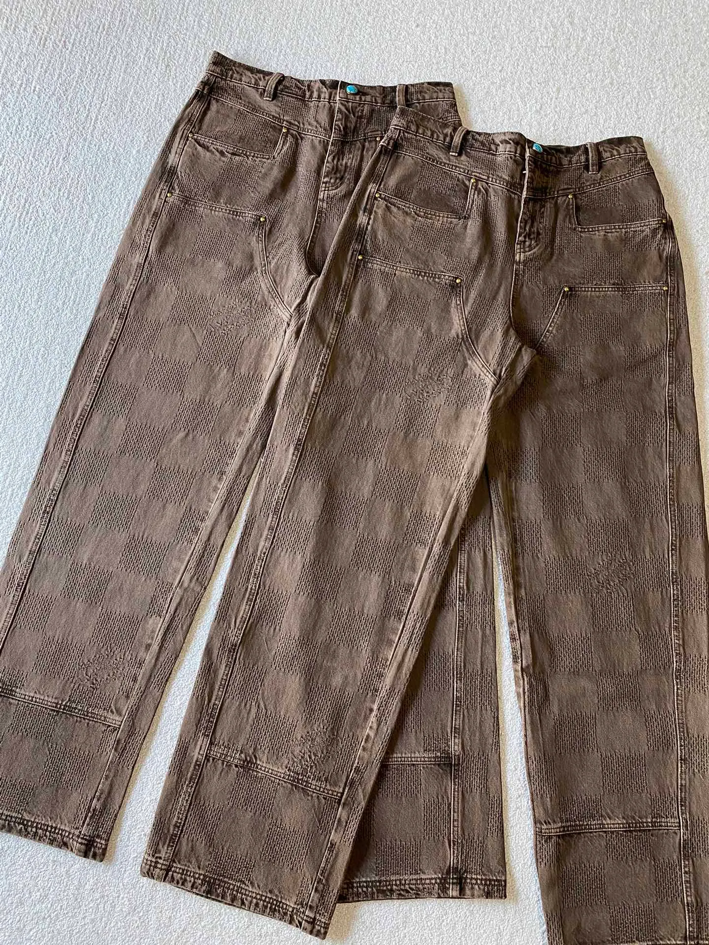 LU brown checkerboard denim straight trousers ⚠️Original purchase, 600, skateboard straight version, Marque L. Uuitton deposee logo integrated into 3D Damier jacquard, back Damier label, sand washed distressed, topstitch sewing, placket distressed hardware closure #Logo integrated into 3D Damier jacquard 3D Damier jacquard denim fabric is an innovative fabric that combines jacquard technology and the characteristics of denim cloth. The classic plaid pattern is combined with 3D jacquard technology to weave three-dimensional patterns on the fabric through a loom.  The fabric presents an exquisite plaid pattern in appearance, and the pattern is made three-dimensional and layered through jacquard technology. At the same time, it retains the original tough, wear-resistant and durable properties of denim, making the clothes more durable.  # Sandwashed, Faded and Distressed Effect Sandwashed, faded and distressed denim fabric is a specially treated denim fabric that exhibits a whitened and distressed effect. This fabric uses a sand-washing process and special dyeing technology to create a natural wear and fading effect on the denim after washing, making it look more vintage and historical.  #skateboard straight jeans version Skateboard jeans are usually designed to be looser to accommodate the large movements and squatting postures during skateboarding. Jeans have a straight shape and a consistent width from hip to hem. Suitable for all body types, these straight-leg skateboard pants are designed with comfort and freedom in mind for skateboarding.