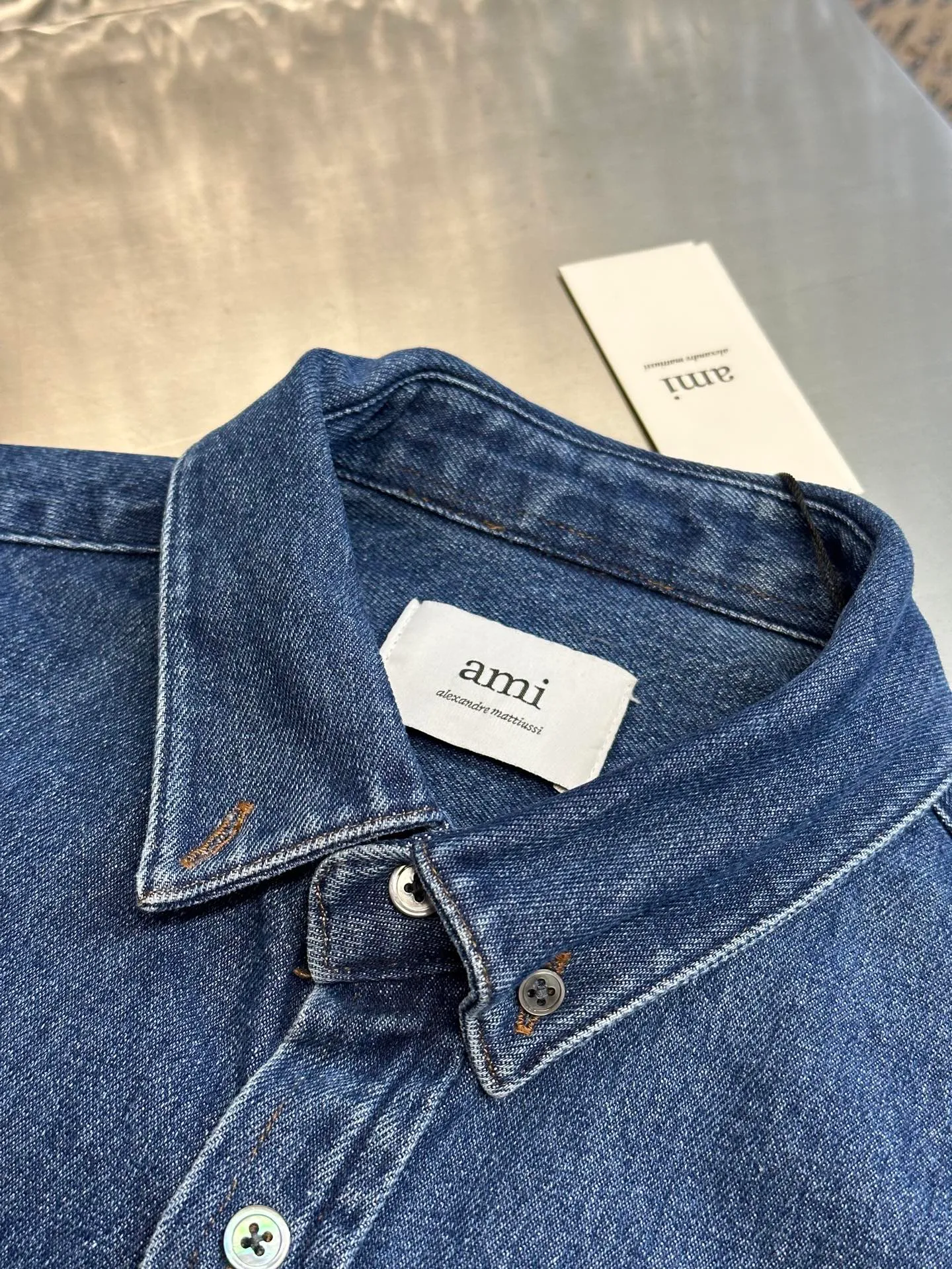 🅿️480 Ami Paris denim shirt jacket. Customized cotton essence denim fabric with a deep denim blue background and a bright red heart on the chest, injecting agility and elegance into the tough denim.  Using sand-fried hand-rubbing technology, the surface of the denim material will be naturally faded and worn by processing on a sand-fried sand machine. Then, special tools are used to physically damage the surface of the jeans by hand, maintaining the original texture and details while increasing its uniqueness. Stir-fried snowballs, stir-fried salt, specially prepare the corresponding solution, add a certain amount of dye, soak the denim material in it to absorb the solvent, and then scrub and dry it to further fade and oxidize it.  size：s m l xl