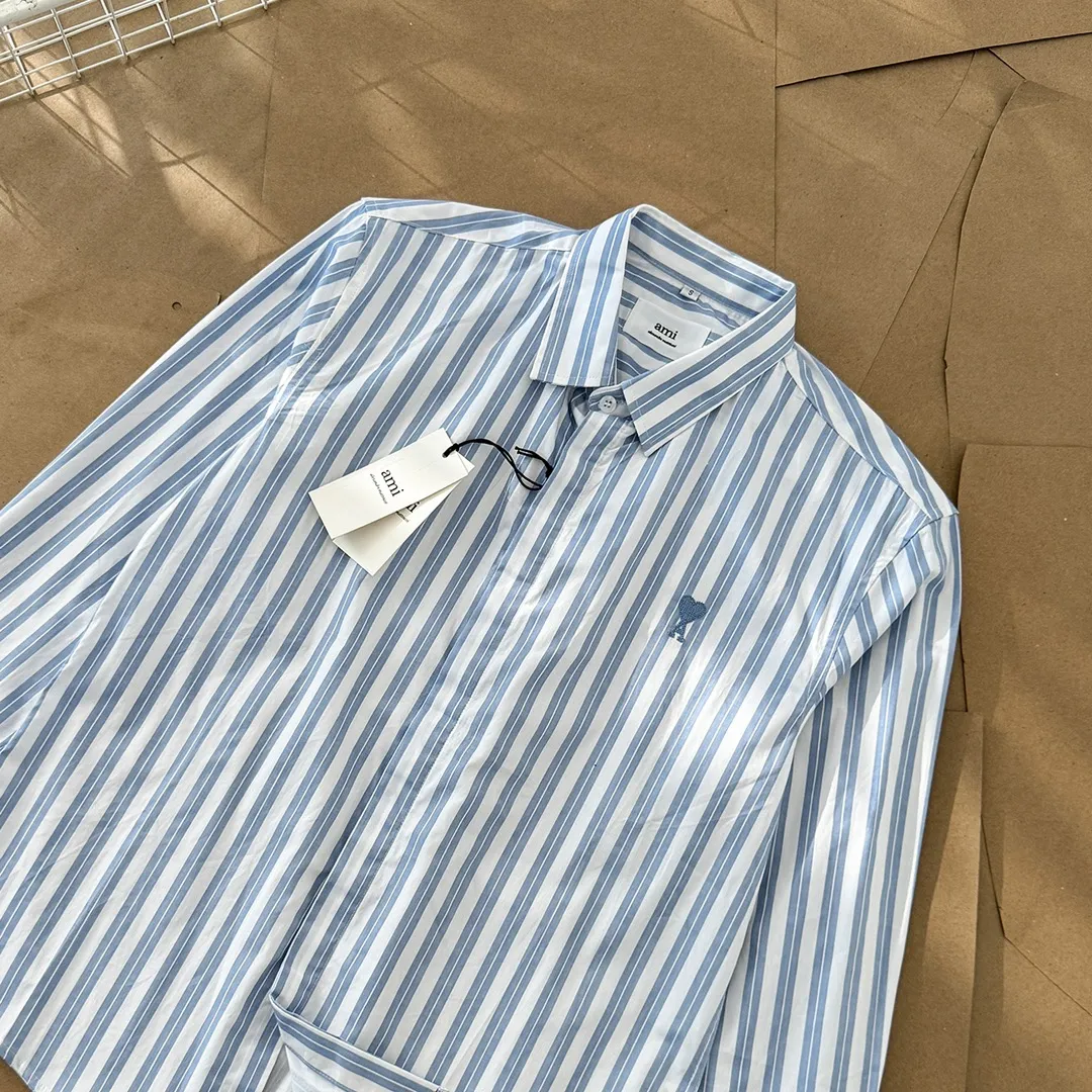 Ami Paris Oxford cotton button-down corner collar casual shirt-blue heart thick striped long-sleeved shirt-same style for men and women. Blue small love letter embroidery decoration fashionable and versatile long-sleeved shirt! On sale simultaneously at counters!  A well-known French affordable luxury fashion brand. The brand's classic elements are embellishments sought after by major celebrities. Its basic simple design and fashionable style make it a must-have couple's shirt for men and women!  Made of custom-woven 100% Oxford cloth pure cotton, it feels soft and delicate, has excellent moisture absorption and perspiration performance, and is very comfortable and skin-friendly when worn next to the skin! The chest of the shirt is decorated with the classic love letter A logo embroidery. The top-notch embroidery technology is tight, full and full of details, and is cleverly embellished with bright red. It carries all the eye-catching points. It follows the consistent minimalist French attitude. The fabric is soft and comfortable, suitable for any versatile casual shirt couple!  Color: Blue Stripe Size: S-XL S: Bust 106 Shoulder Width 47 Clothing Length 71 Sleeve Length 60 M: Bust 110 Shoulder Width 48 Clothing Length 73 Sleeve Length 61 L: Bust 114 Shoulder Width 49 Clothing Length 75 Sleeve Length 62