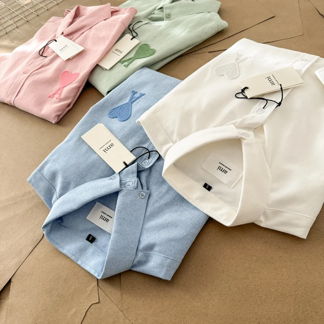 Ami Paris same color large heart embroidered Oxford cloth cotton button corner collar casual shirt - same style for men and women. Fashionable and versatile long-sleeved shirt with same color letter embroidery decoration! On sale simultaneously at counters!  Made of custom-woven 100% Oxford cloth pure cotton, it feels soft and delicate, has excellent moisture absorption and perspiration performance, and is very comfortable and skin-friendly when worn next to the skin! The chest of the shirt is decorated with the classic love letter A logo embroidery. The top-notch embroidery technology is tight, full and full of details, and is cleverly embellished with bright red. It carries all the eye-catching points. It follows the consistent minimalist French attitude. The fabric is soft and comfortable, suitable for any versatile casual shirt couple!  Color: Green Pink White Blue Size: S-M-L-XL Shoulder Width: 47-48-49-50 Bust: 106-110-114-118 Length: 71-73-75-76 Sleeve Length: 60-61-62-63