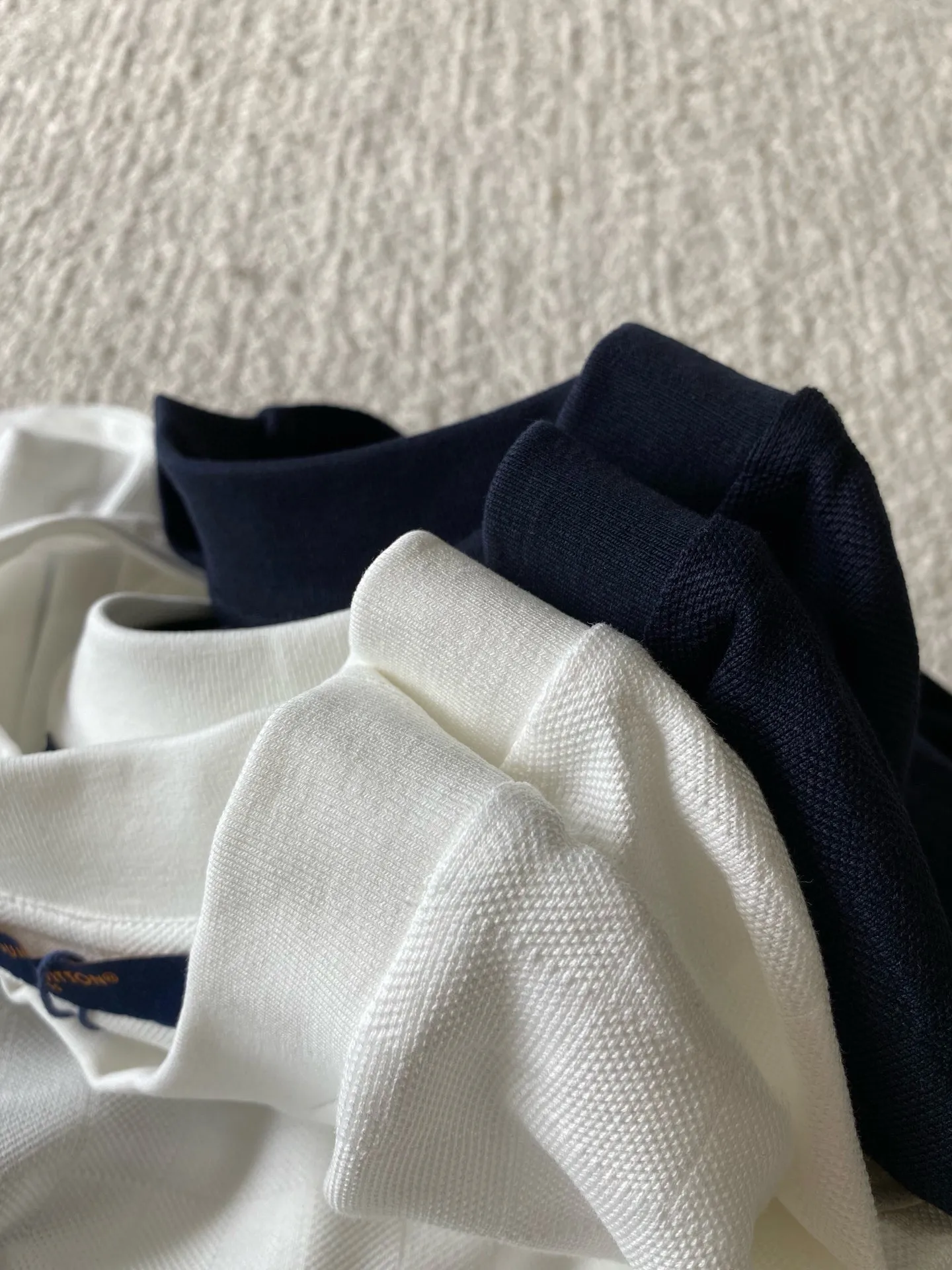 LU piqué round neck short sleeves. Available colors: navy blue, apricot white. ⚠️Original, 350 purchase; piqué jacquard fabric, standard version, full-width Damier jacquard piqué, chest Marque L.Uuitton déposée embroidery #full-width Damier jacquard piqué Navy blue · 32S double strand, 210g; apricot white · 80S double strand, 120g; with 32S double yarn thread, 320g. Pique jacquard fabric is a special fabric woven using a jacquard machine, with highly beautiful patterns and high-quality feel. This kind of fabric uses jacquard processing technology and uses various jacquard structures to make the yarns show a plaid pattern and form a bead-like finish on the surface of the fabric. The unique texture and visual effects of the fabric make it highly artistic.  #Chest Marque L Uuitton deposee embroidery The chest is embellished with simple letter patterns, and the letter size spacing effect is consistent. Using linen embroidery thread combined with encrypted processing, the embroidery body has a subtle matte visual texture; the embroidery effect is three-dimensional and full. The smaller the embroidery, the more sophisticated and demanding it is. The embroidery thread is made of imported material, which is more flexible and glossy than ordinary embroidery thread; the stitches are clear and smooth, and have a three-dimensional texture effect.  #Positioning Pattern Cutting and Sewing The whole piece positioning pattern sewing process is a fine and complex technology. During the cutting process, it is necessary to ensure that the pattern or texture of each piece can perfectly match other pieces. Through floral tailoring, the checkerboard pattern of ready-made garments appears neatly arranged.  #straight round neck version. Cut and sewed in floral position, standard H hanging version, with shoulder-length design. The vertical version emphasizes that the width of the shoulders, waist, and hem are basically the same, and it is simple and loose. The short sleeves are tailored to fit the body of the wearer. At the same time, the neckline, cuffs and hem of the short sleeves are all designed with double lines.